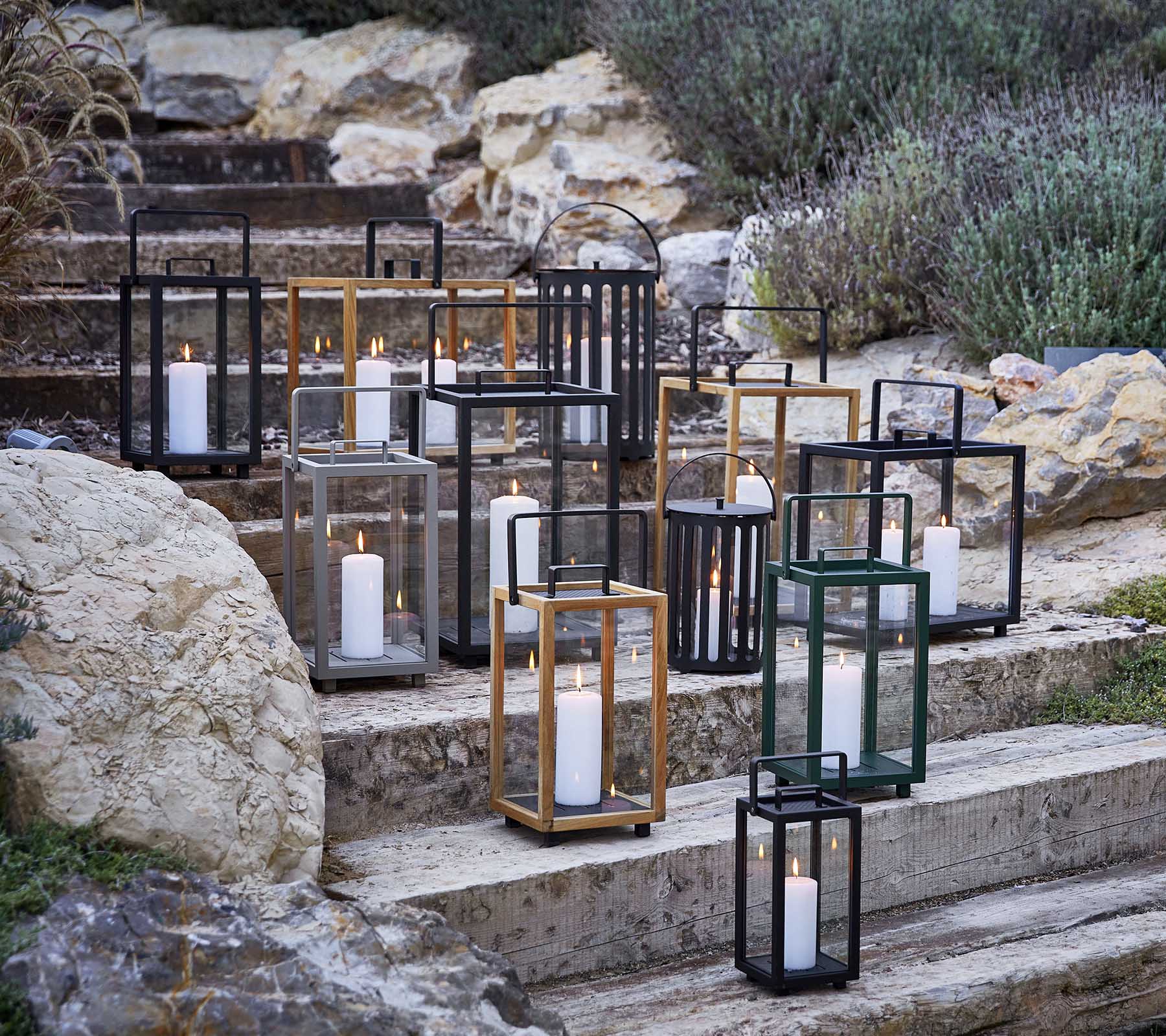 Collection de lanternes décoratives dans divers styles et couleurs, avec une douce lumière de bougie, artistiquement disposées sur des marches en pierre.