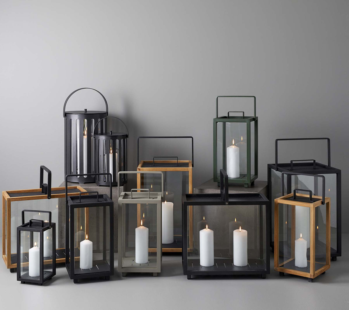Une collection de lanternes élégantes de différentes tailles et styles, contenant des bougies à l'intérieur, disposées ensemble sur un fond neutre.