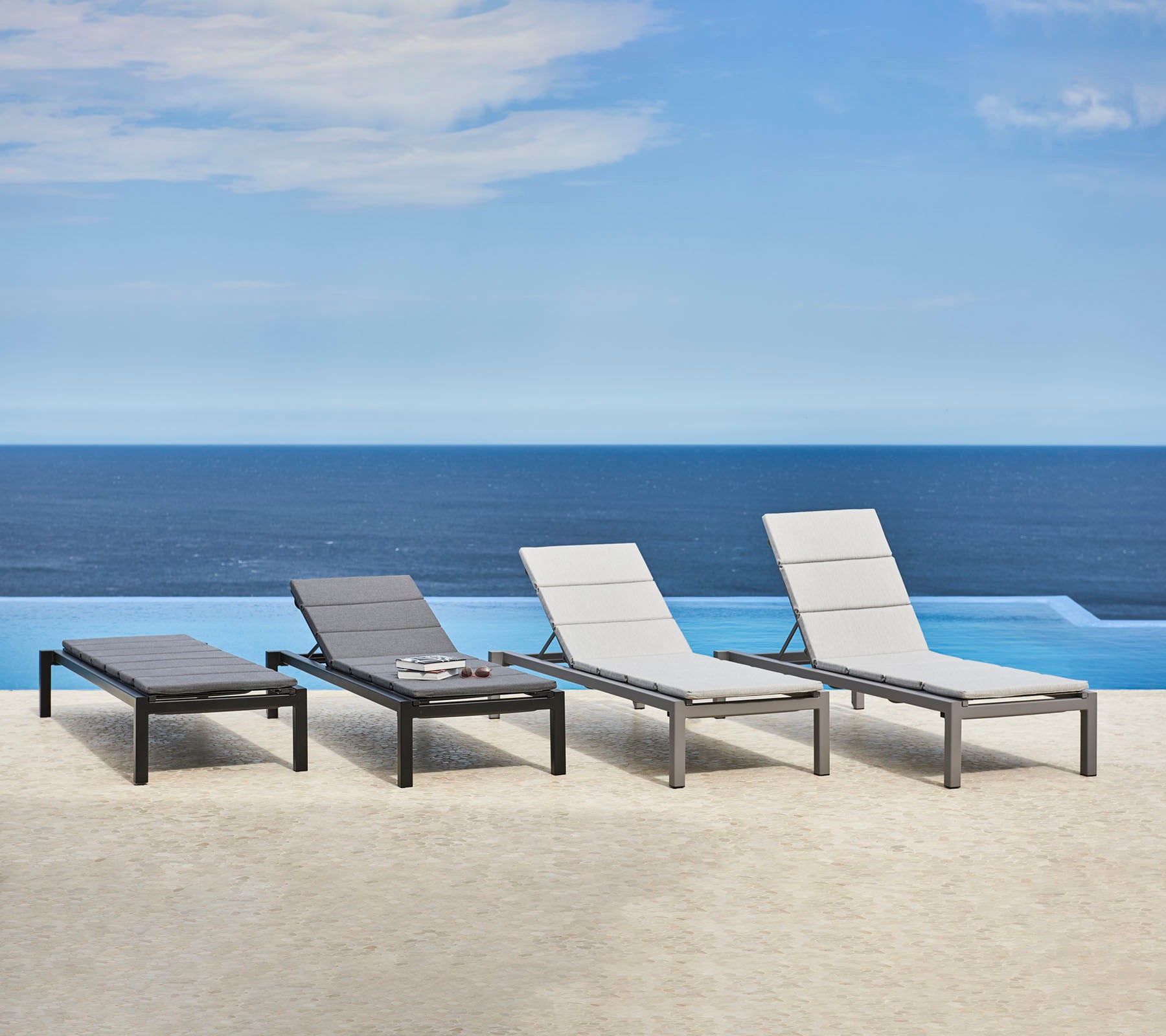 Quatre fauteuils lounge élégants au design épuré, positionnés près d'une étendue d'eau sereine, créant un espace de relaxation tranquille.