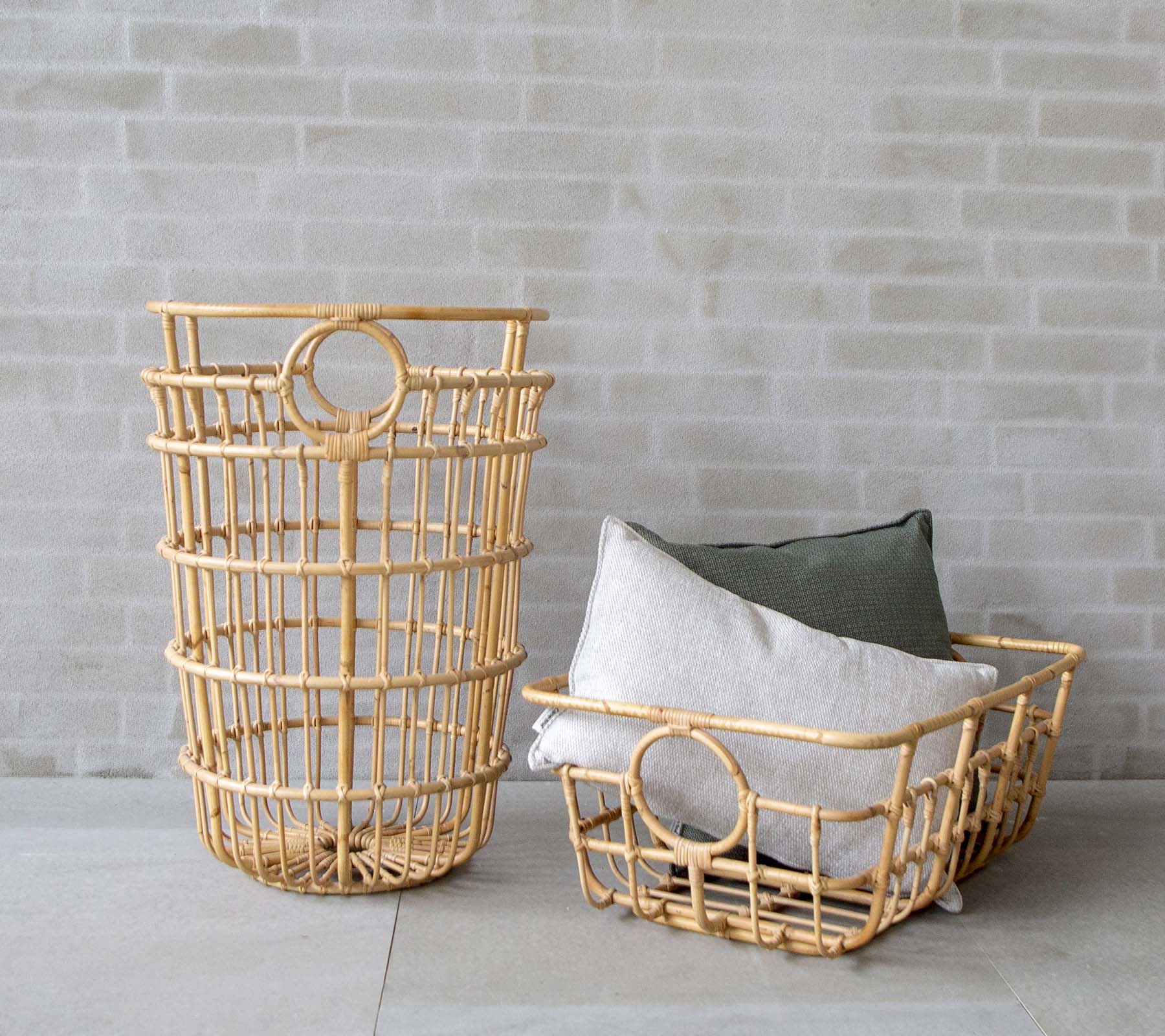 Des paniers modernes en osier avec des coussins gris et verts dans un cadre minimaliste.
