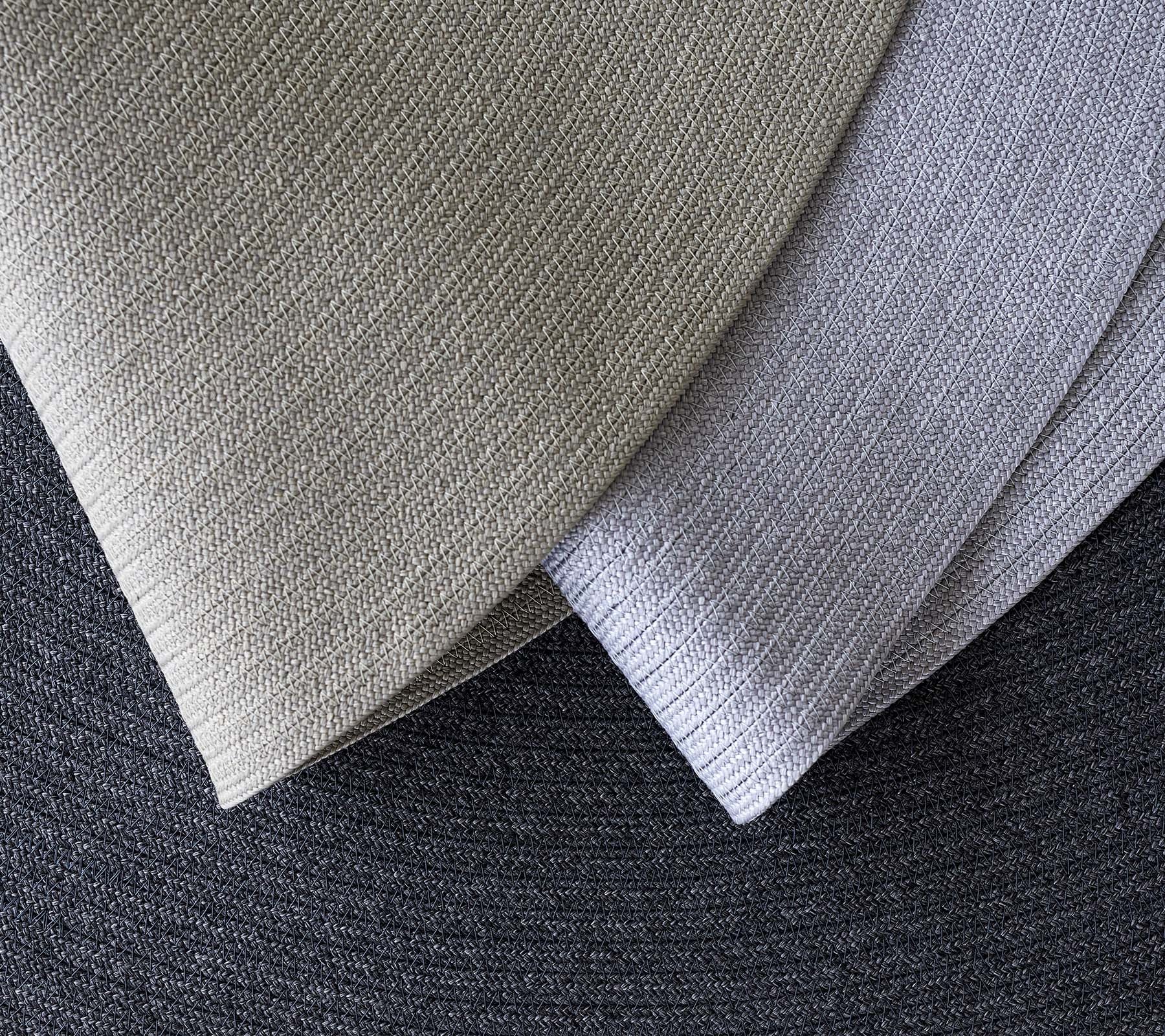 Trois tissus texturés superposés dans différentes nuances de gris, mettant en valeur différents motifs et tons pour des applications de design.