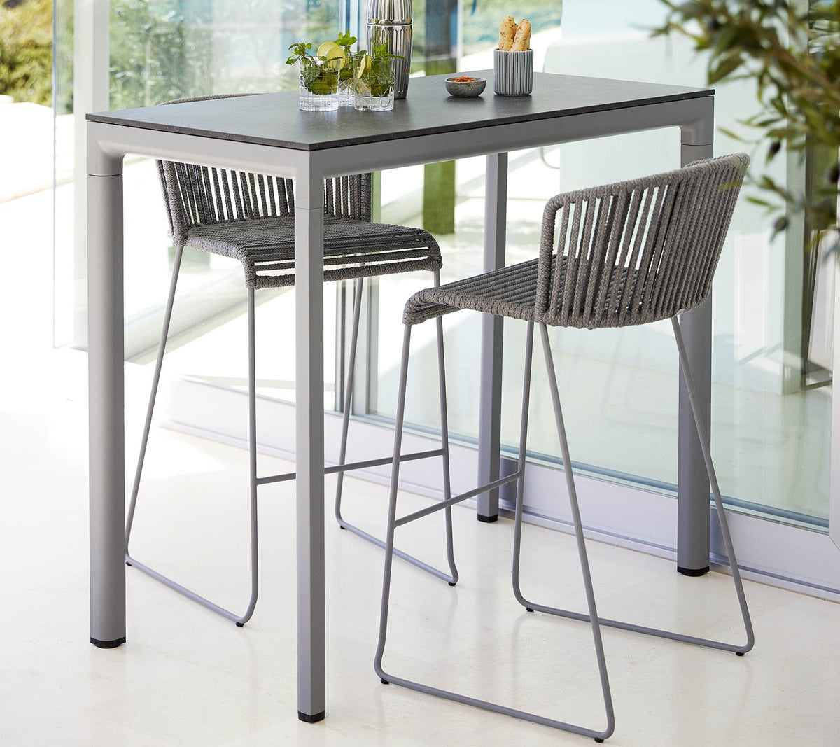 Une table moderne avec une surface lisse accompagnée de deux chaises élégantes à dossier haut, idéales pour des repas décontractés ou des rassemblements.