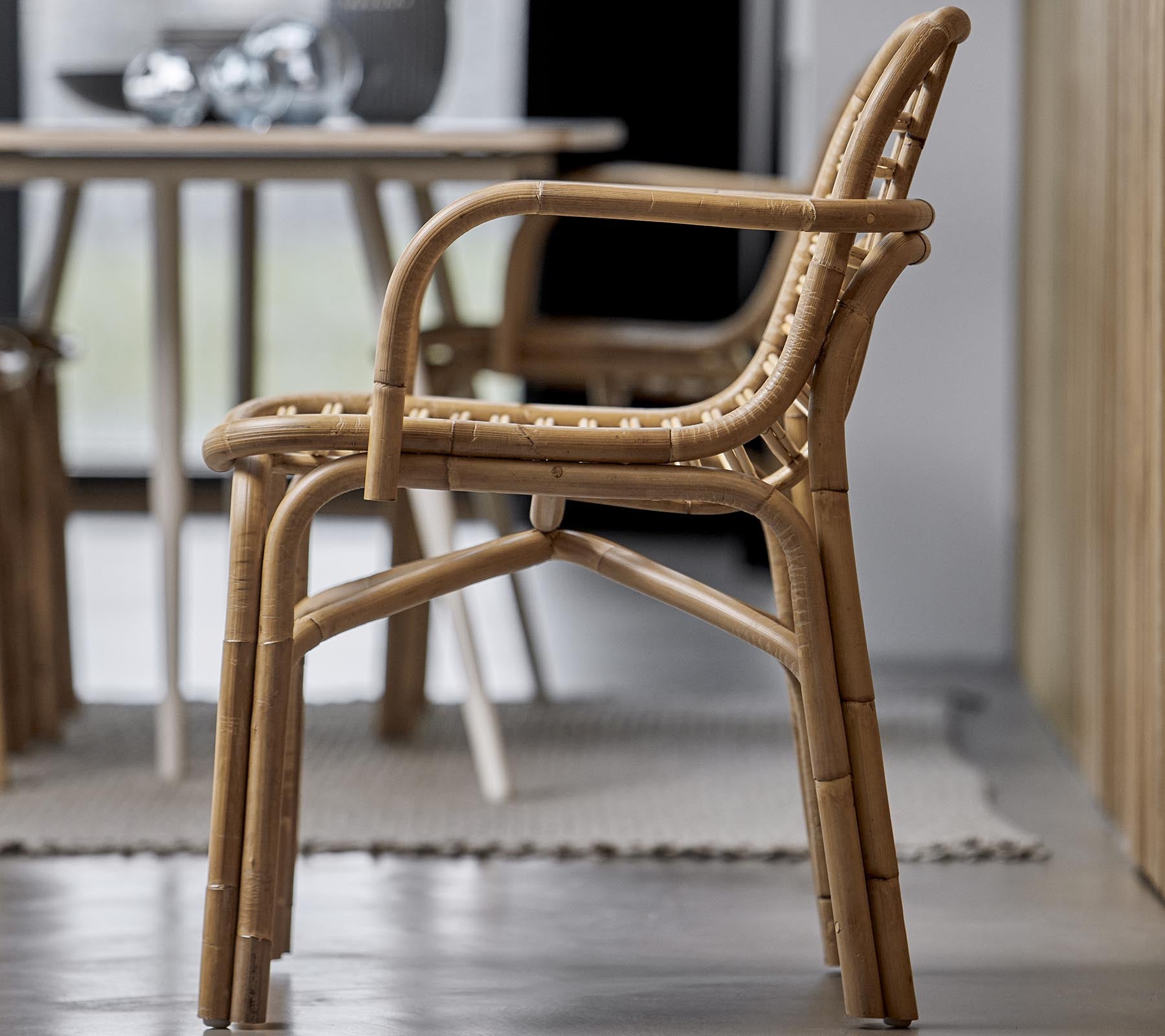 Une chaise élégante en matériaux naturels, avec un design tissé et des accoudoirs, adaptée à divers environnements intérieurs.