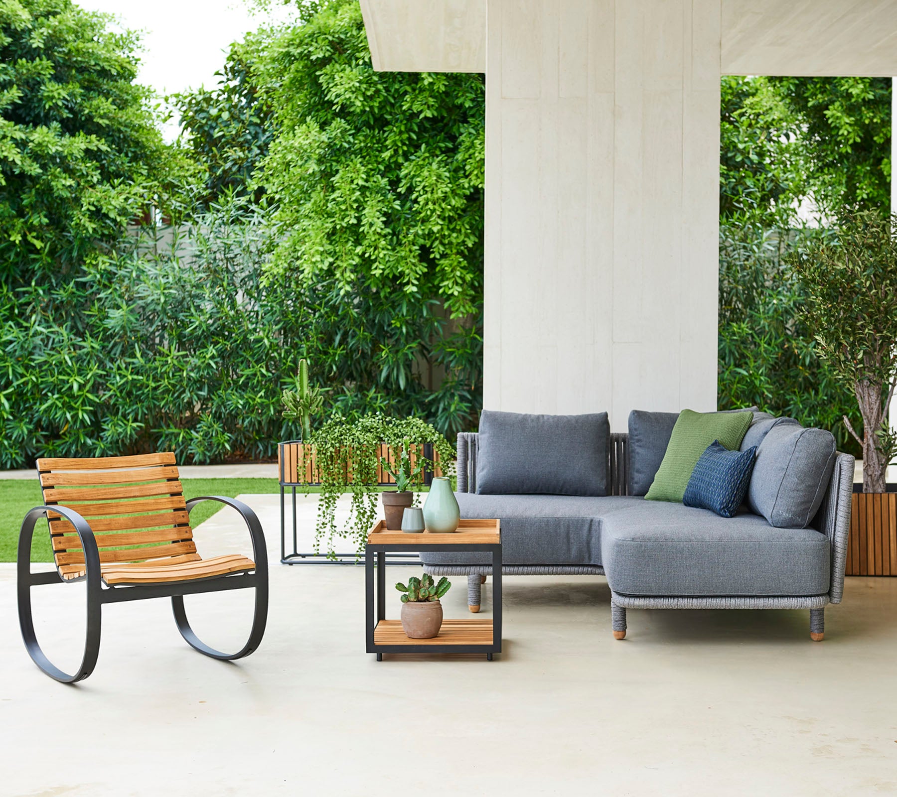 Agencement contemporain avec un canapé modulaire avec des coussins, une chaise élégante et une table d'appoint avec des plantes décoratives.