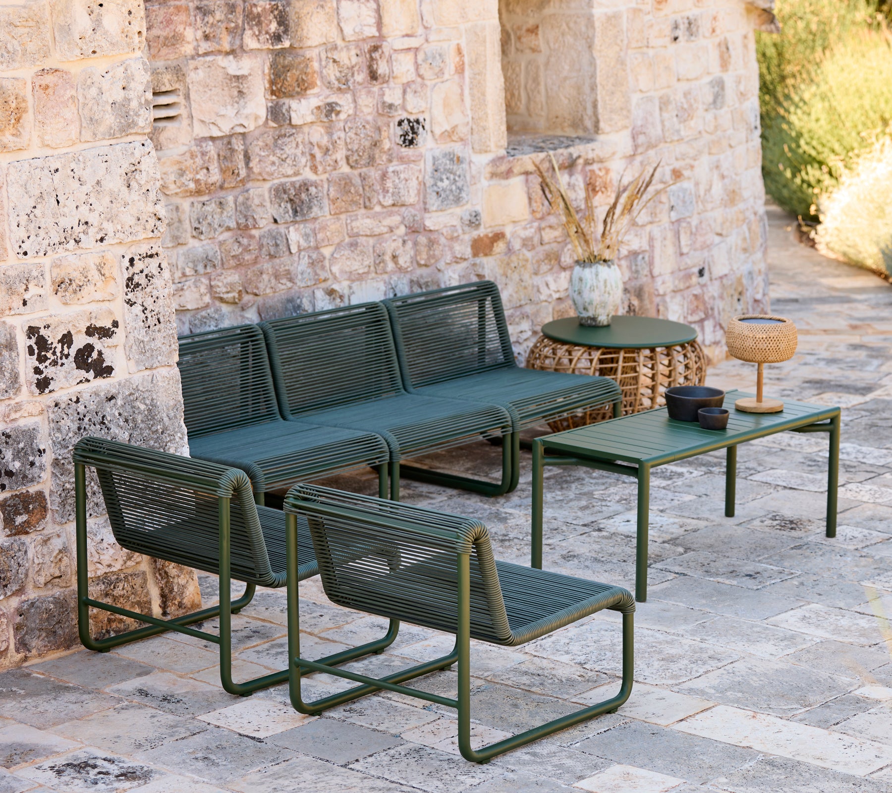 Canapé et fauteuils modernes verts avec une table assortie dans un cadre de salon décontracté.