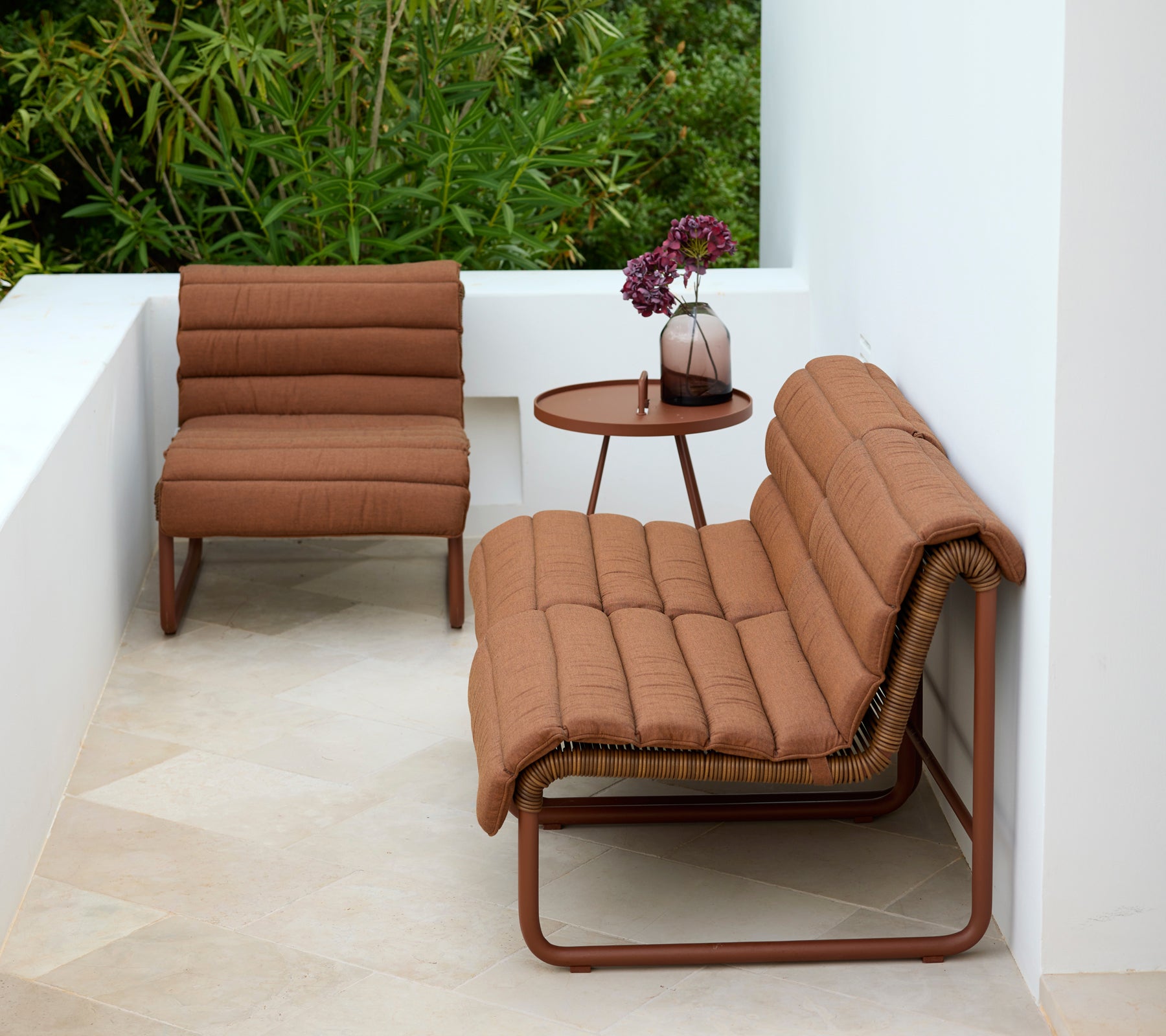 Fauteuil et loveseat marron avec une table d'appoint ronde dans un cadre extérieur moderne.