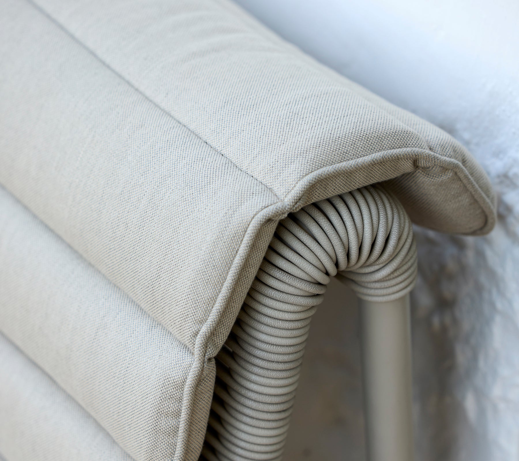 Coussin beige avec une texture côtelée reposant contre un mur clair.
