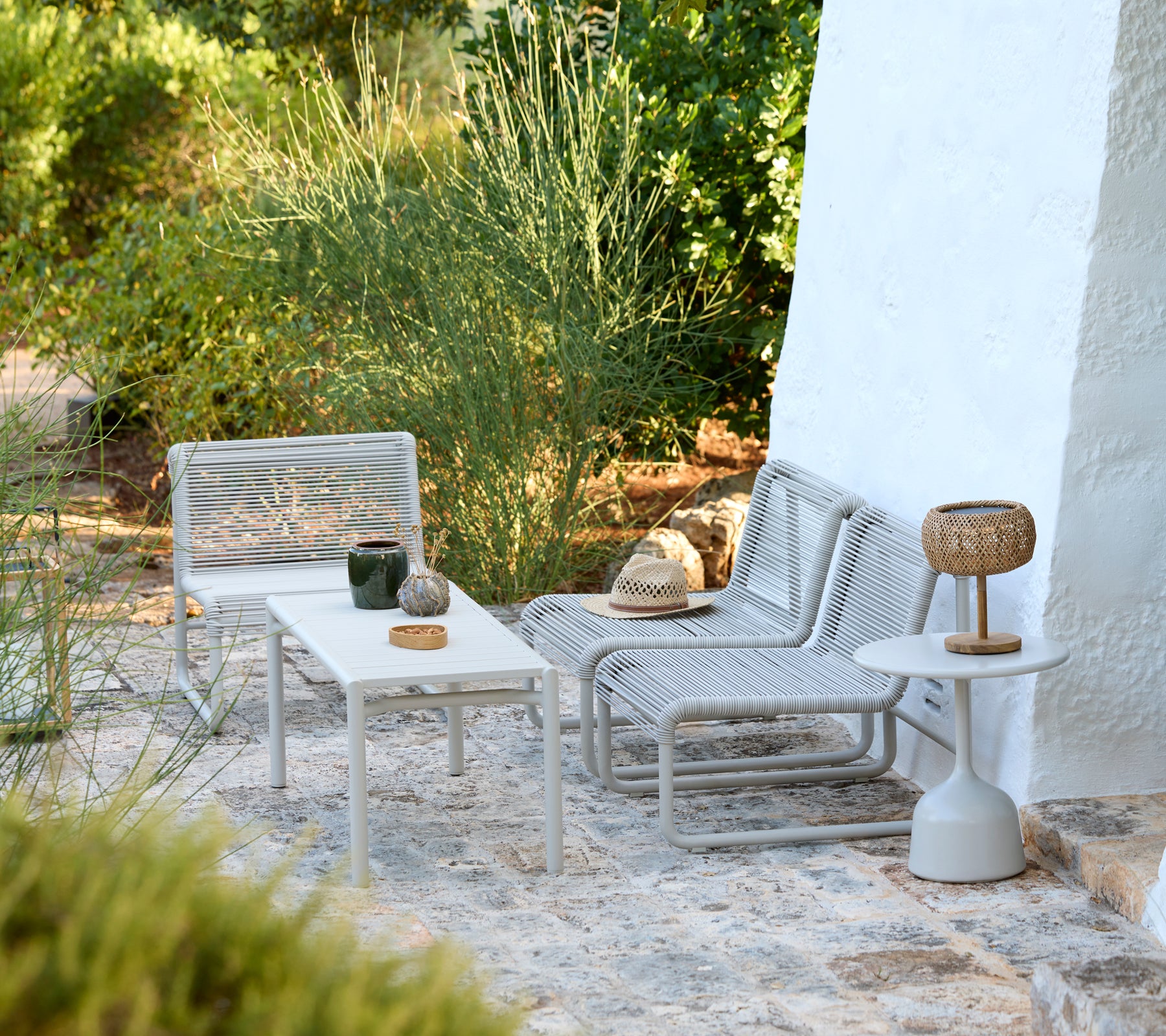 Chaises longues grises modernes et tables blanches dans un cadre extérieur minimaliste.