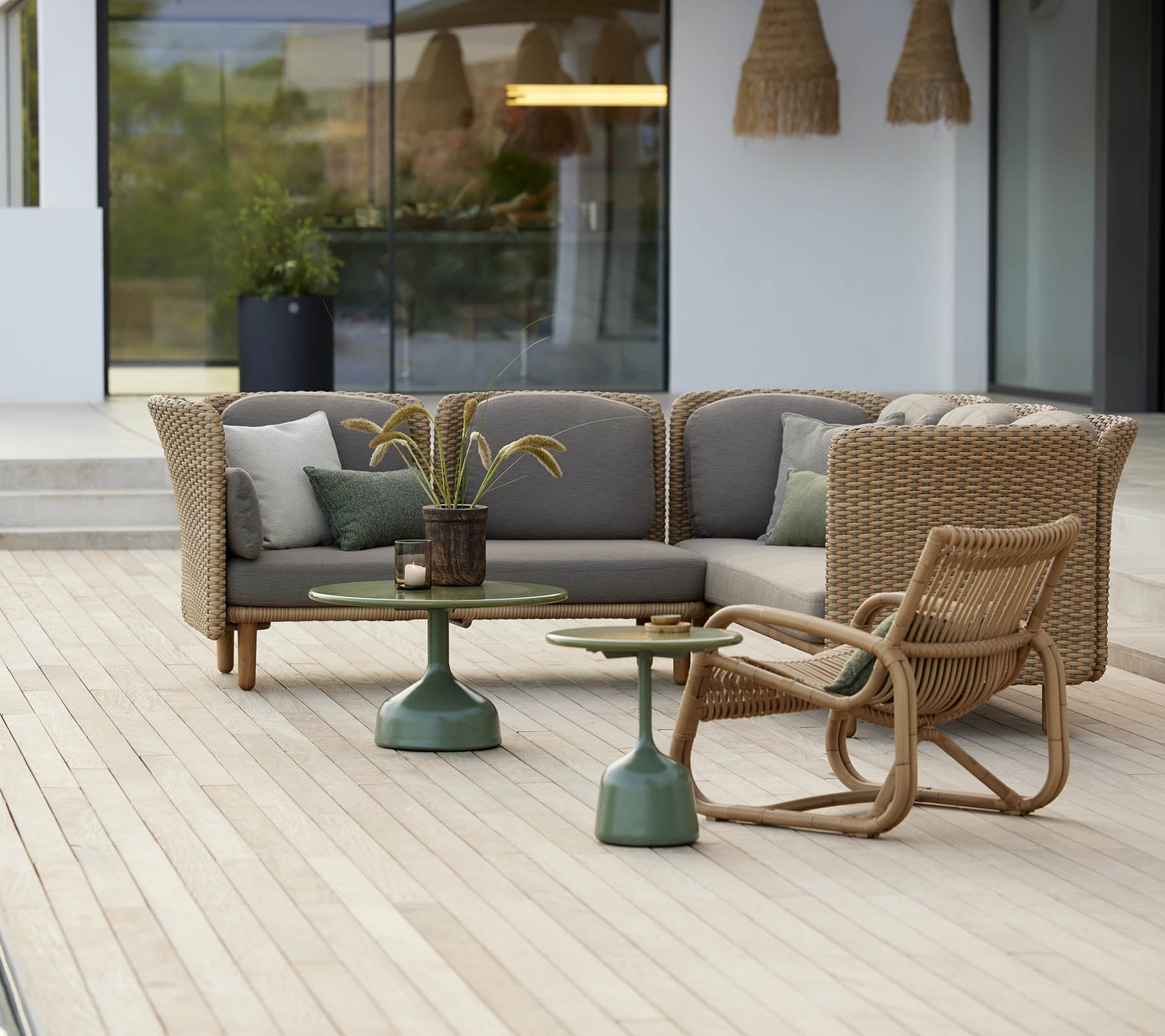 Espace de salon élégant avec un fauteuil incurvé et une table à base verte, agrémenté de coussins doux et d'éléments décoratifs.