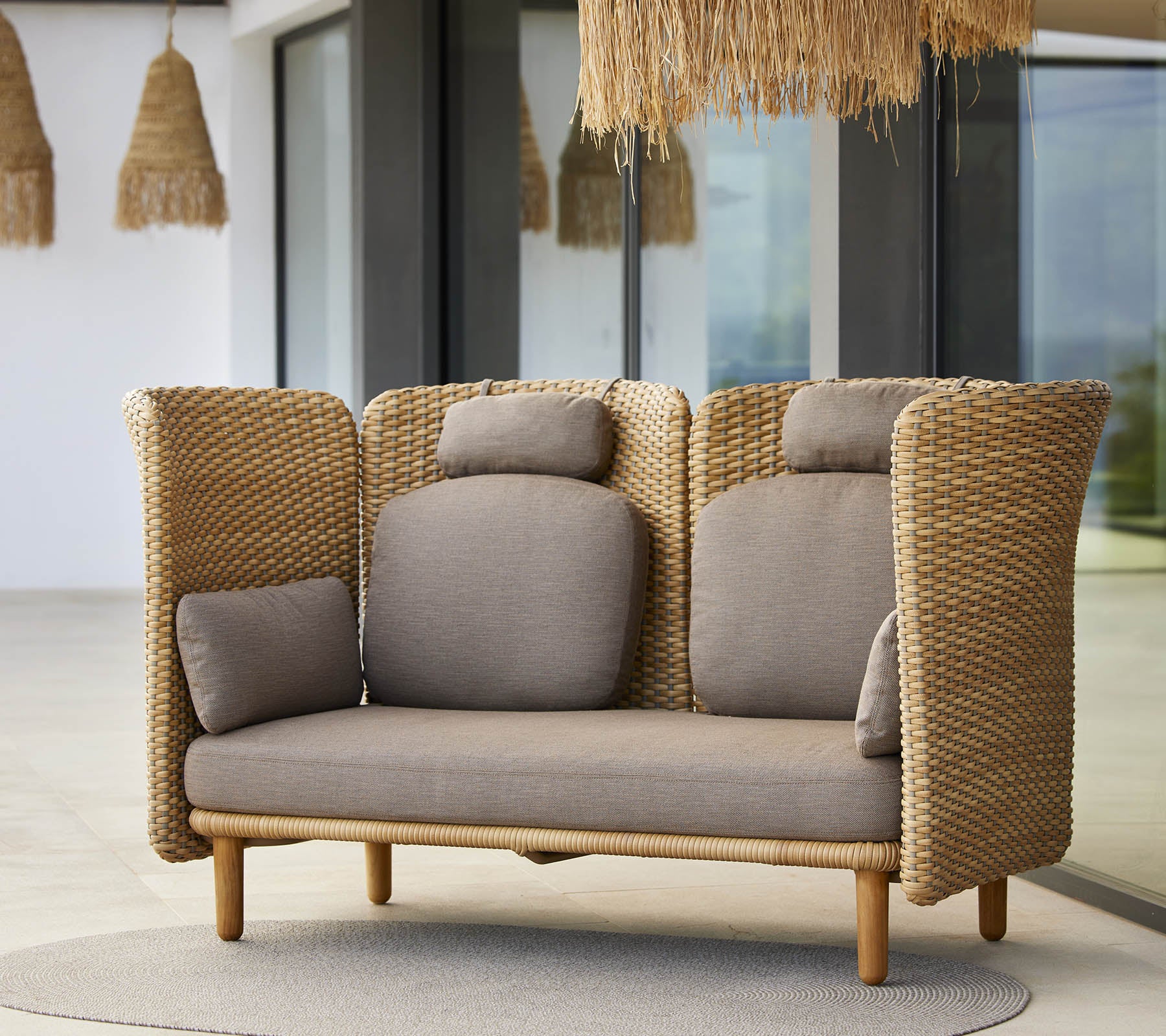 Un canapé lounge élégant avec des côtés tissés et des coussins doux, conçu pour le confort et la détente. Idéal pour les espaces modernes.