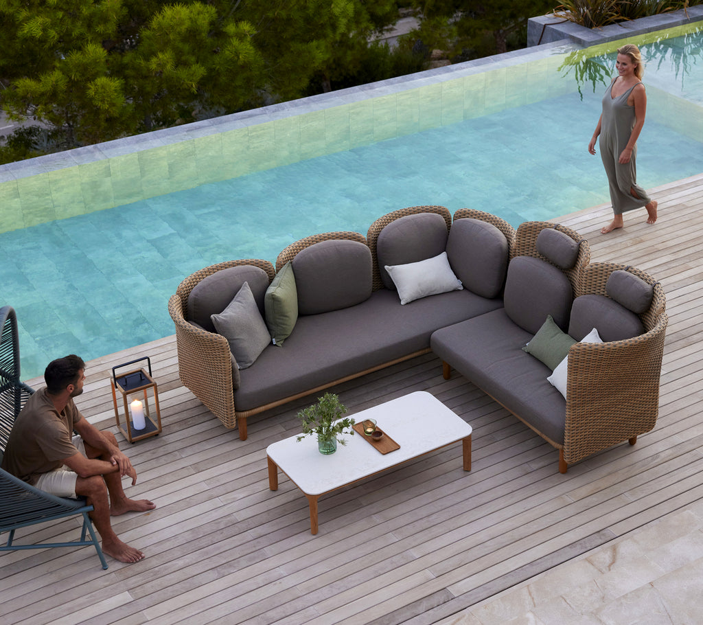 Un canapé arc moderne avec des coussins moelleux et une table basse blanche, entouré de verdure et d'une paisible fontaine d'eau.