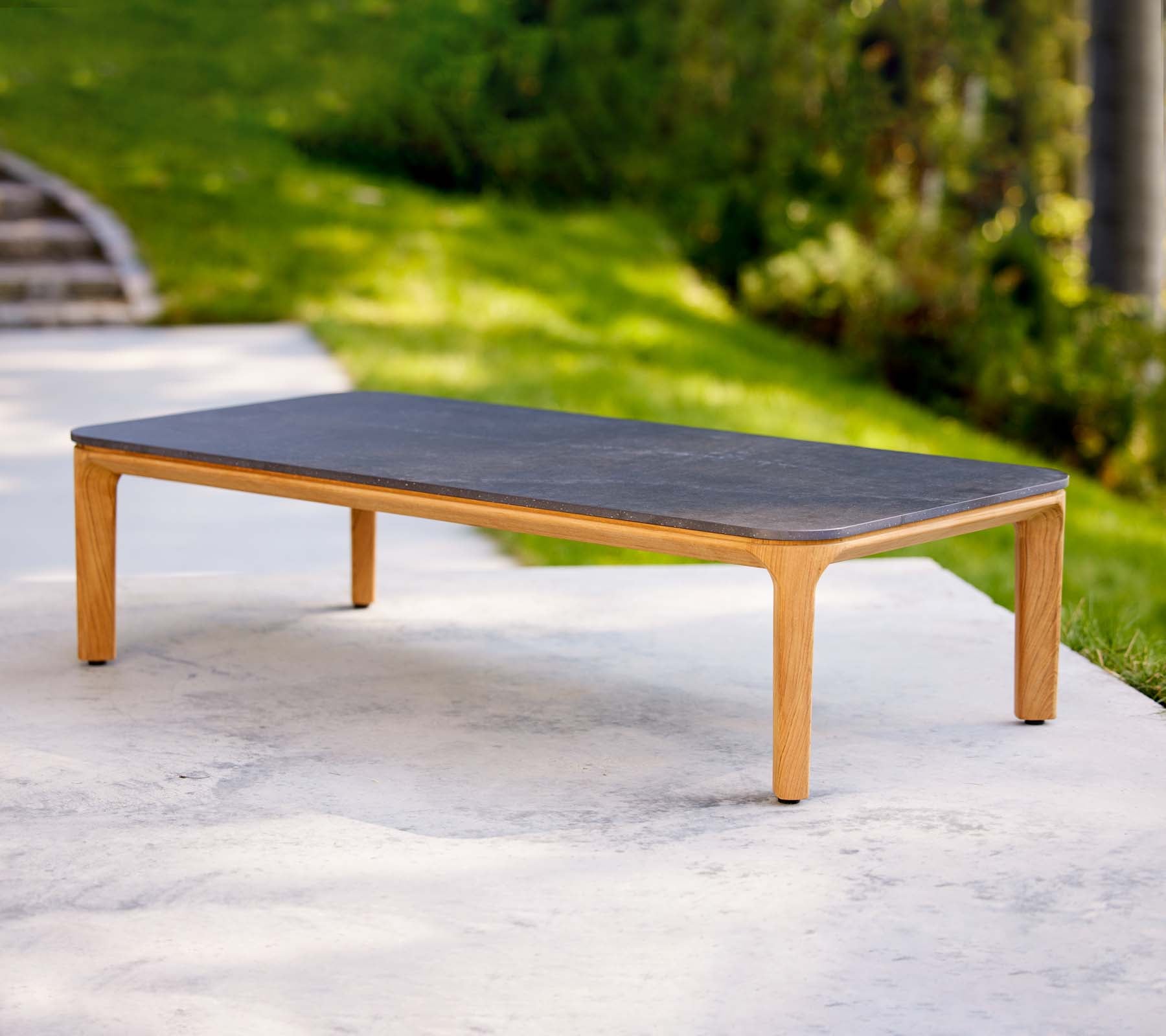 Une table basse élégante avec une surface sombre et des pieds en bois clair, idéale pour les espaces de vie modernes.