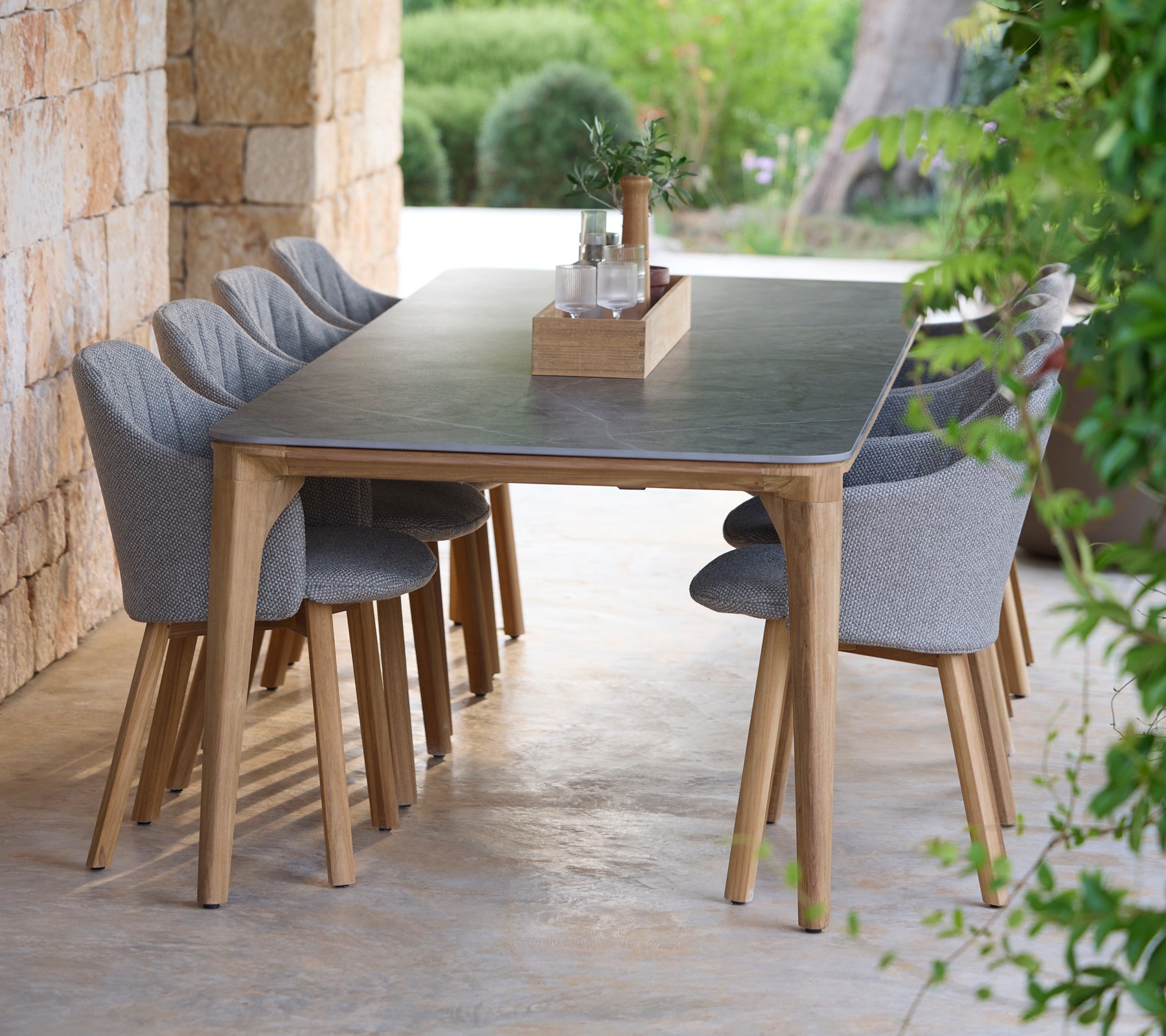 Ensemble de table à manger moderne avec des chaises grises dans un cadre extérieur naturel.