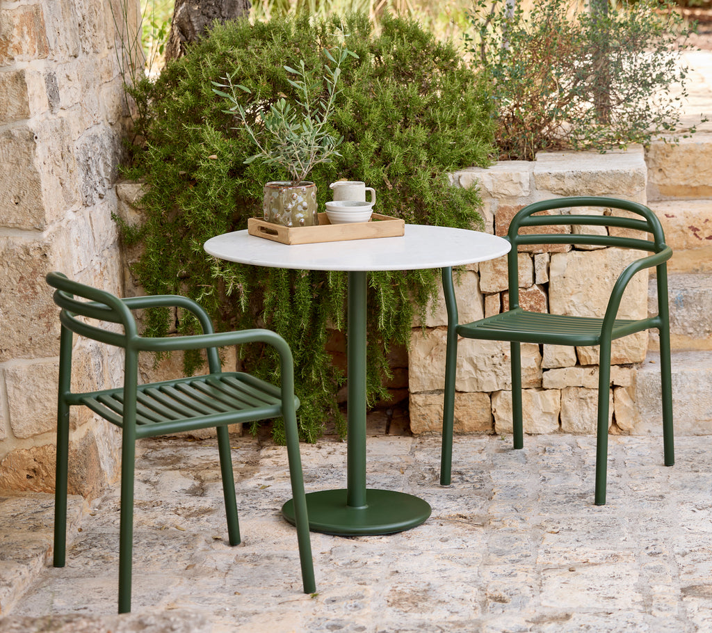 Cadre extérieur moderne avec des chaises vertes et une table blanche.