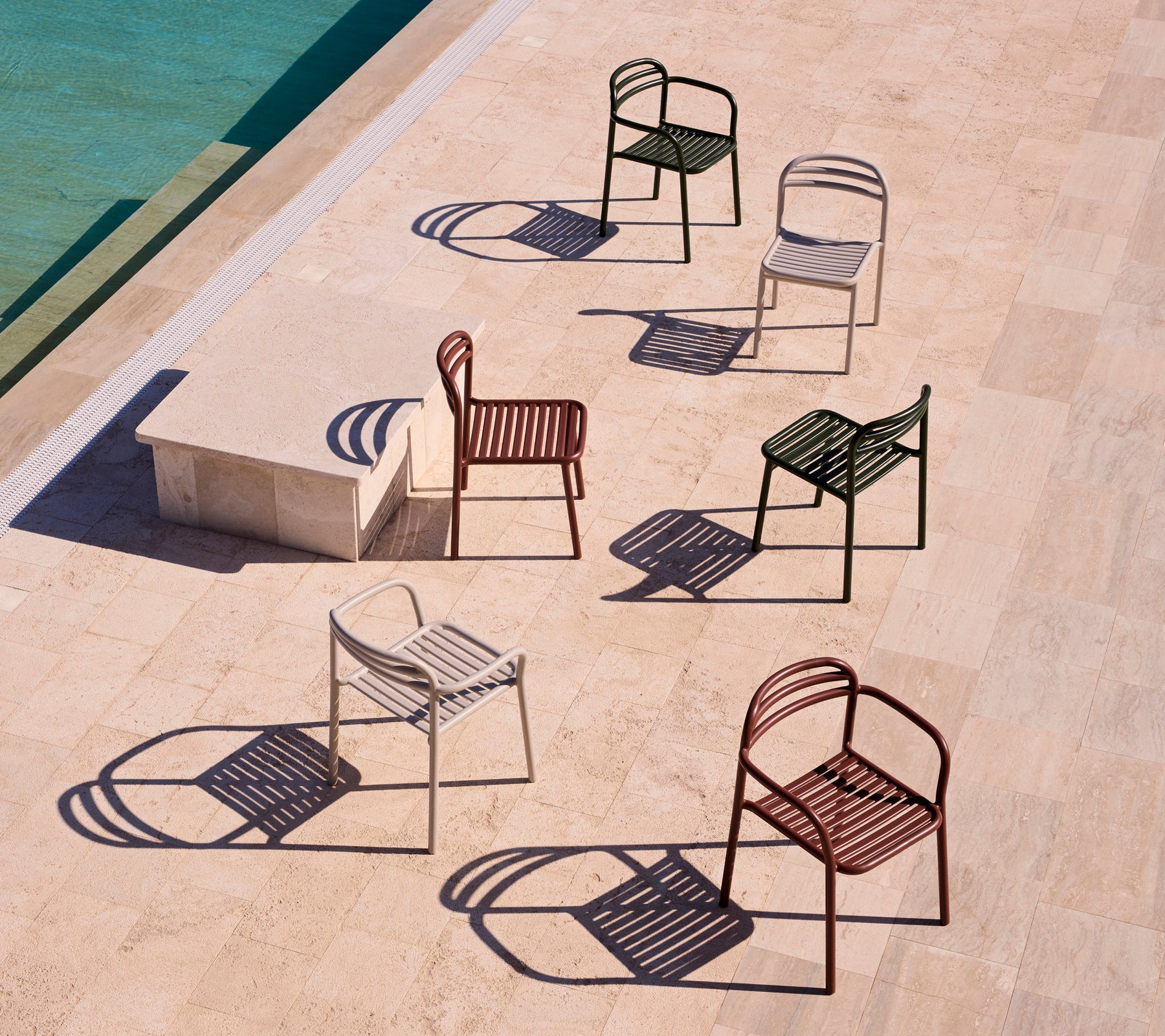 Une collection de chaises Bliss avec accoudoirs dans différentes couleurs, projetant des ombres sur une surface claire.