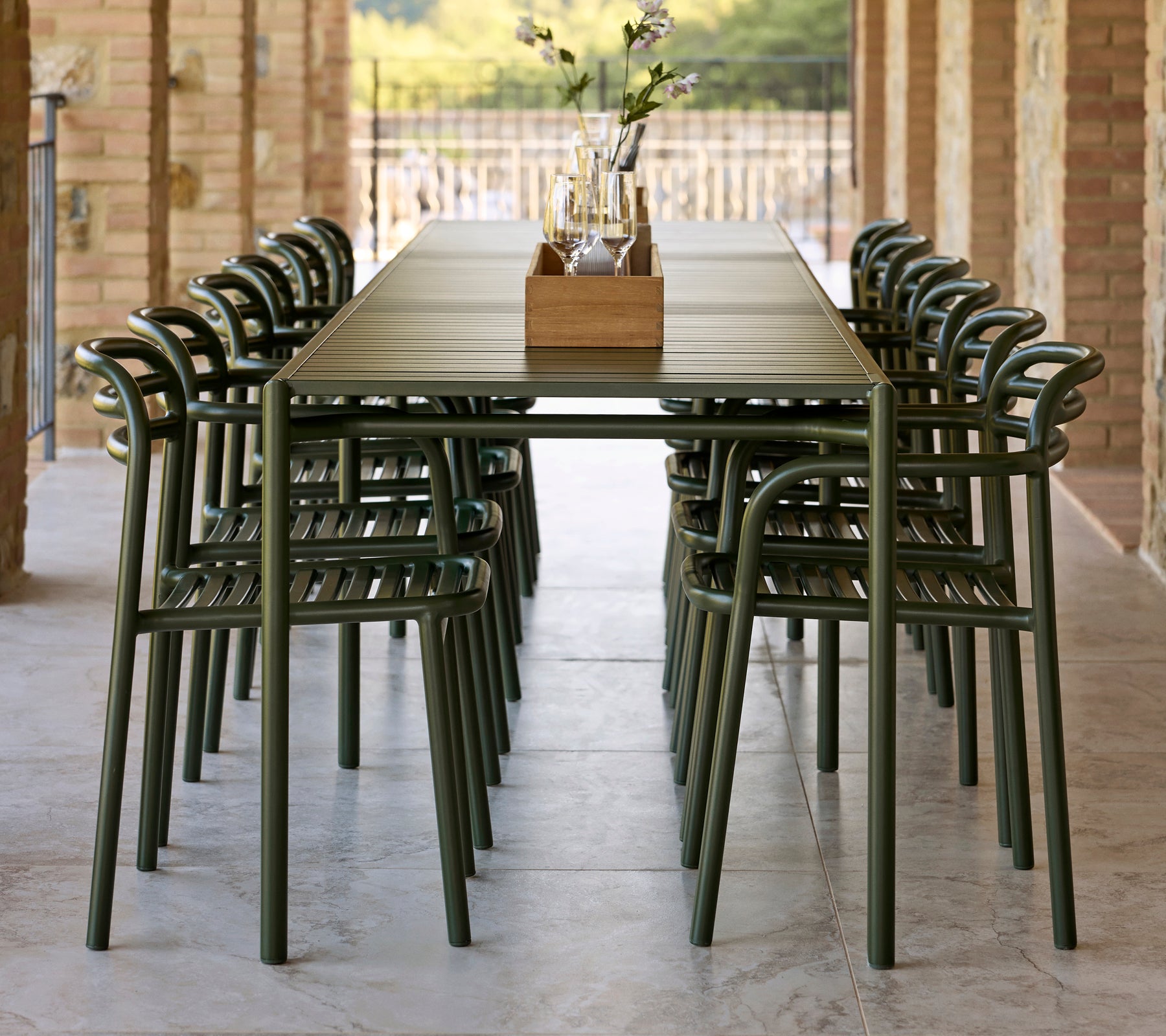 Une longue table ornée de chaises Bliss vert foncé avec accoudoirs, complétée par un centre décoratif.