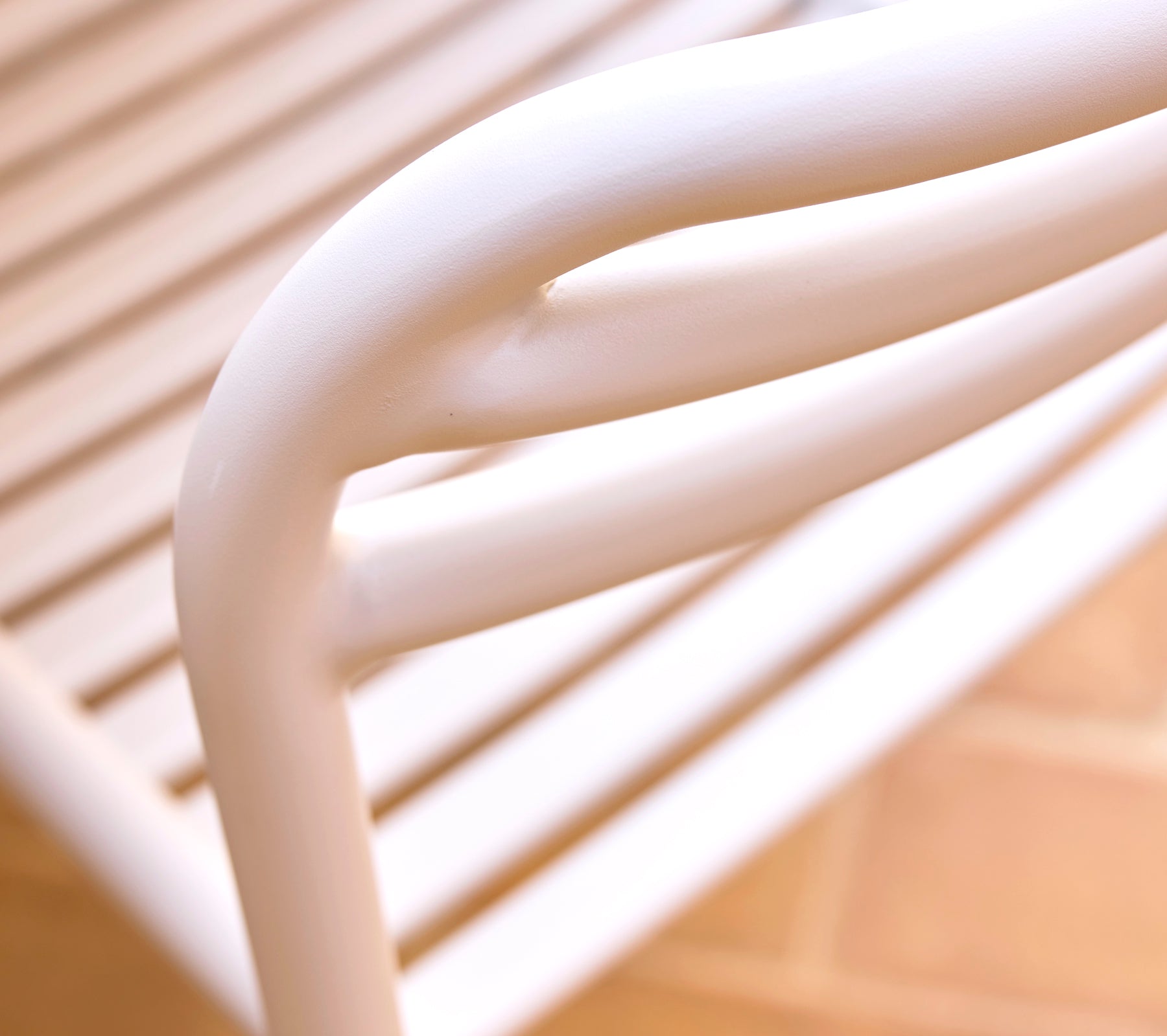 Gros plan d'une chaise de salle à manger couleur sable, mettant en avant des lignes lisses et courbes ainsi qu'un design épuré, soulignant le style moderne et le confort.