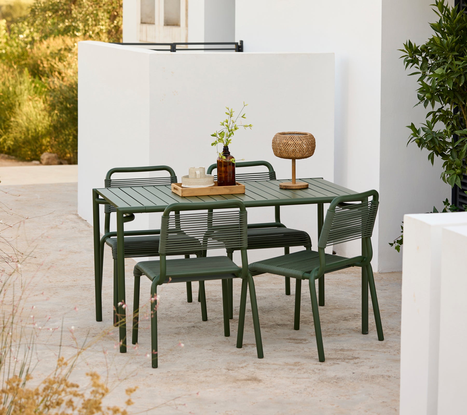 Table verte moderne avec des chaises assorties dans un environnement extérieur.