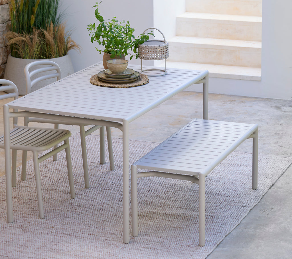 Table à manger blanche moderne avec banc et chaise assortis dans un cadre minimaliste.