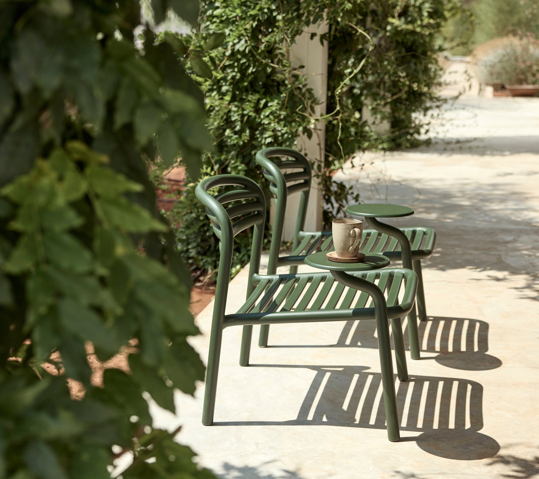 Chaises vertes et table d'appoint dans un cadre extérieur avec une verdure luxuriante.