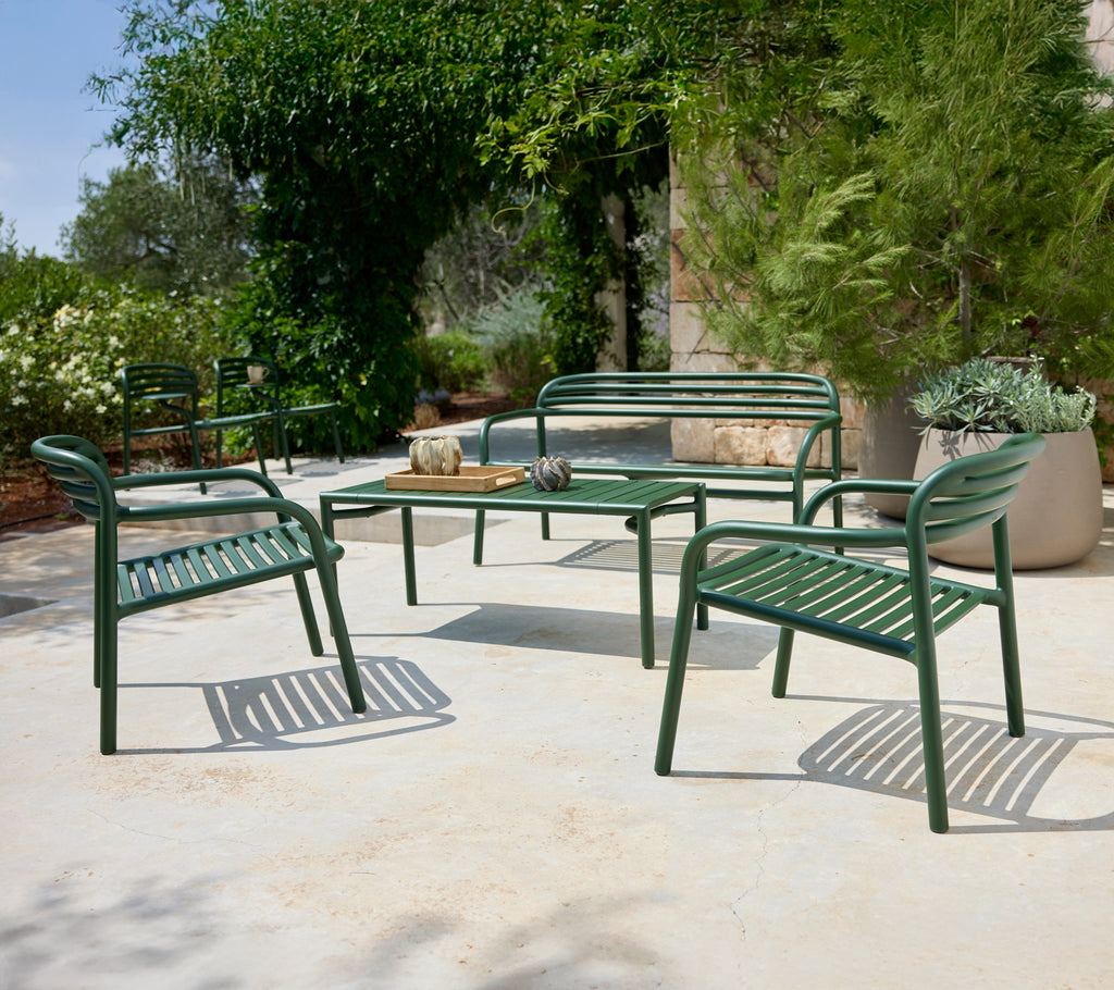 Agencement de sièges extérieurs verts avec des chaises et un banc entourant une table.