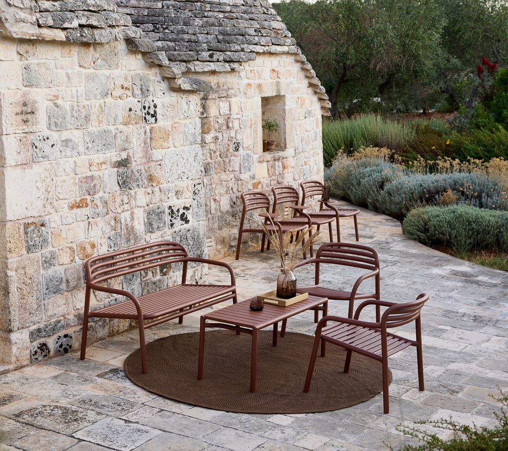 Canapé de jardin brun, chaises et ensemble de table dans un espace lounge moderne.