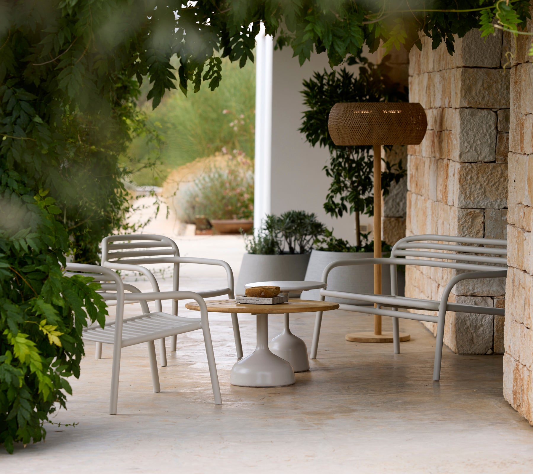 Chaises longues grises modernes et une table blanche à côté d'une lampe en bois dans un cadre extérieur serein.