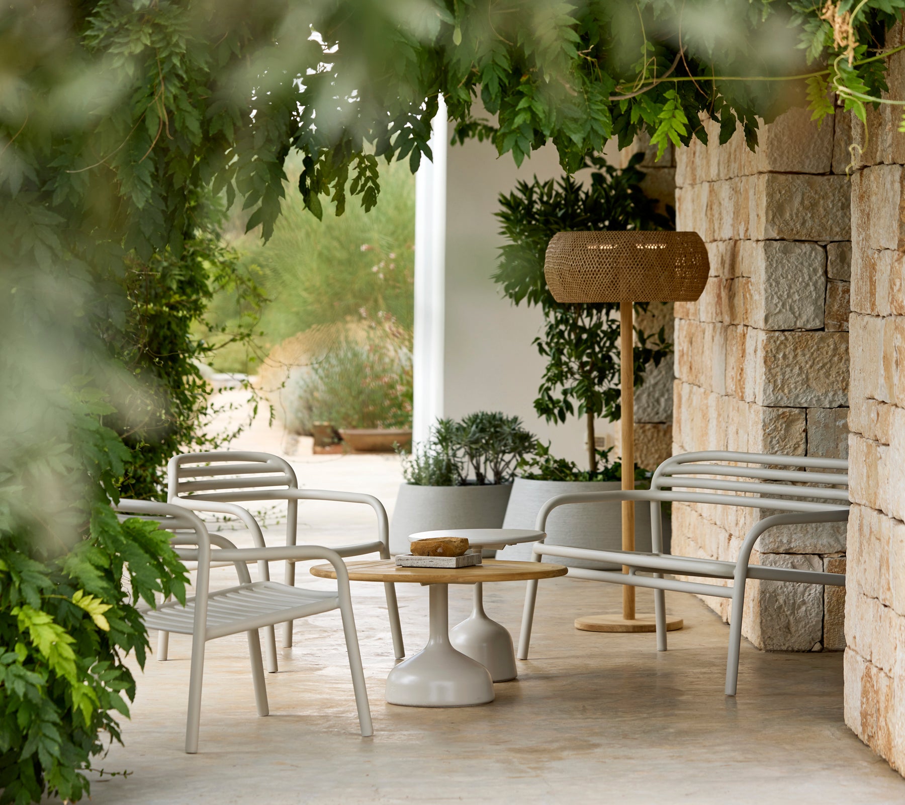 Espace de salon moderne avec des chaises blanches et une table ronde entourée de verdure.