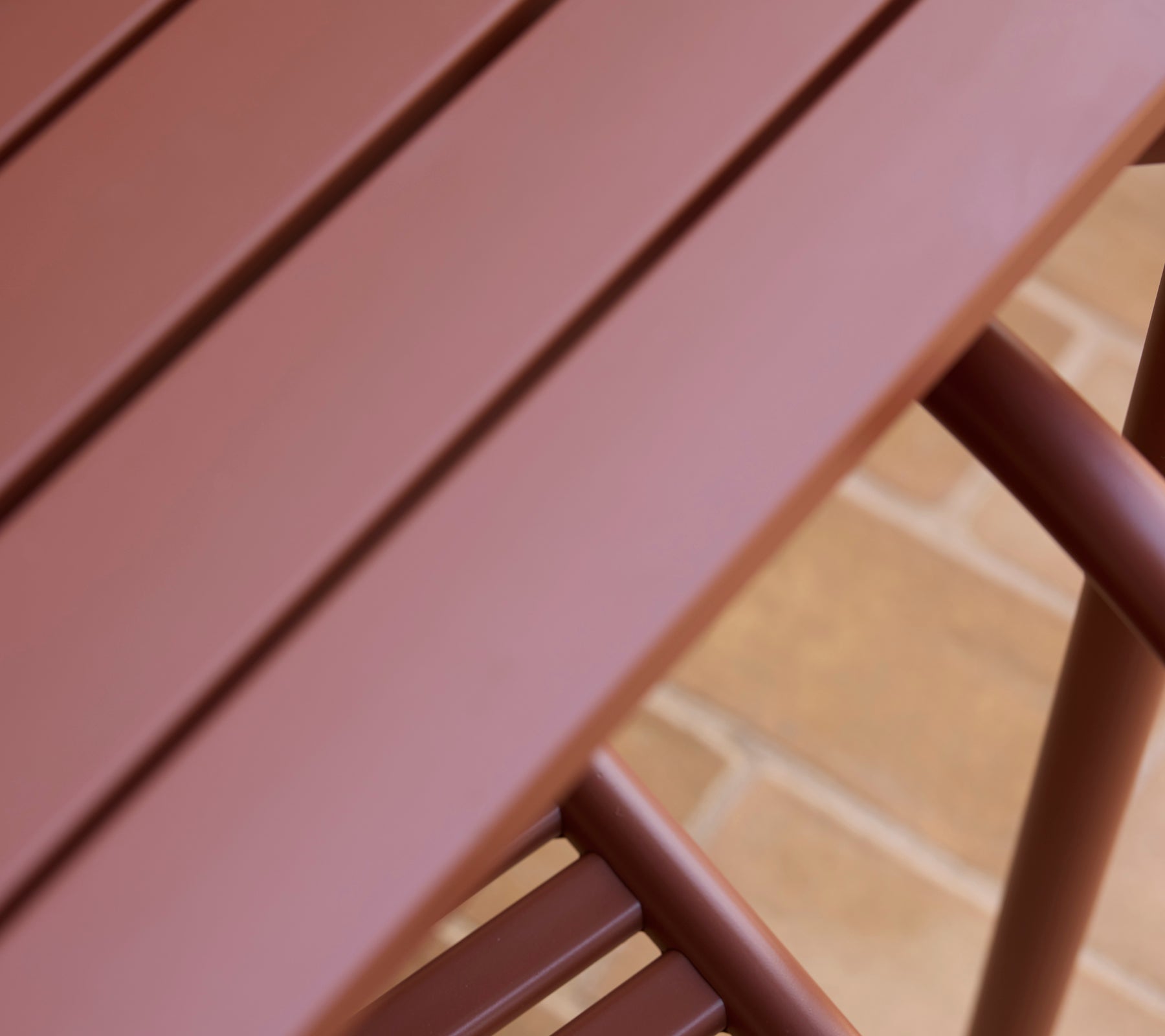 Un gros plan d'une table Bliss rouge désert mettant en valeur sa surface lisse et son design épuré.