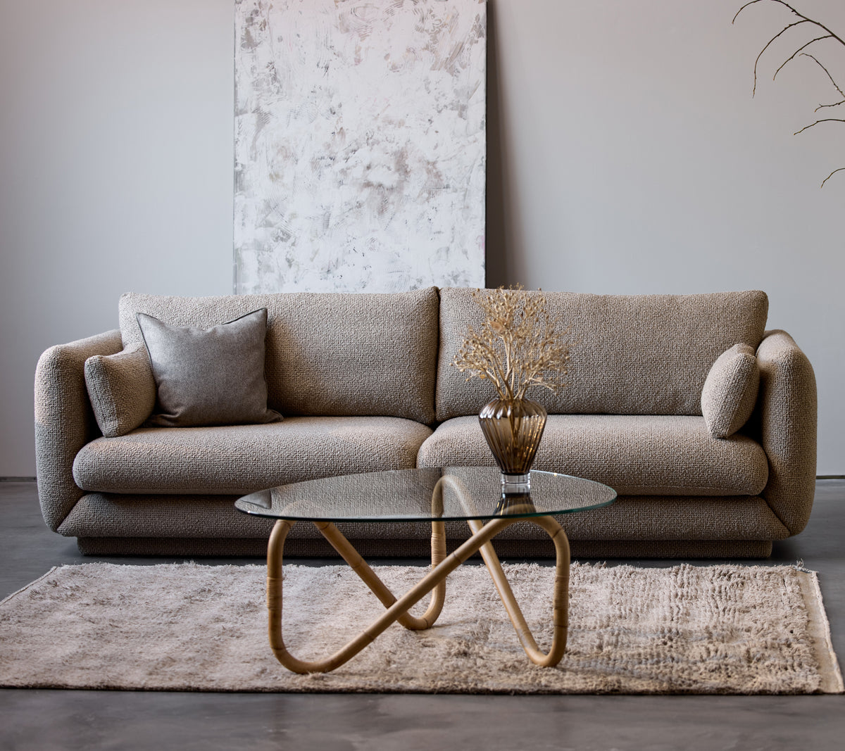 Canapé Bloom 3 places en taupe flair avec un socle, associé à une table basse Wave et un vase décoratif, sur un doux tapis.