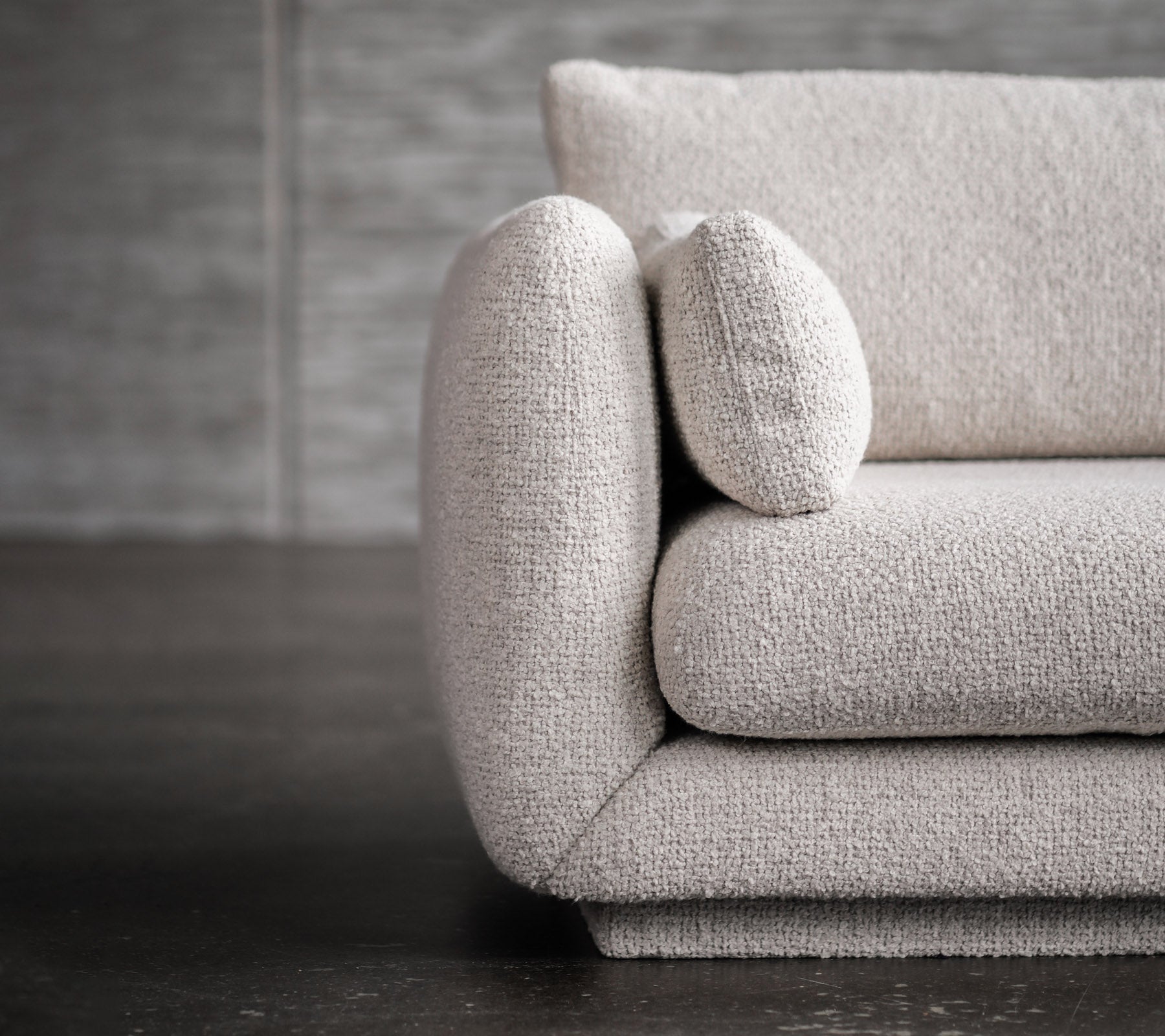 Canapé moderne gris clair avec des accoudoirs arrondis et des détails sur les coussins.