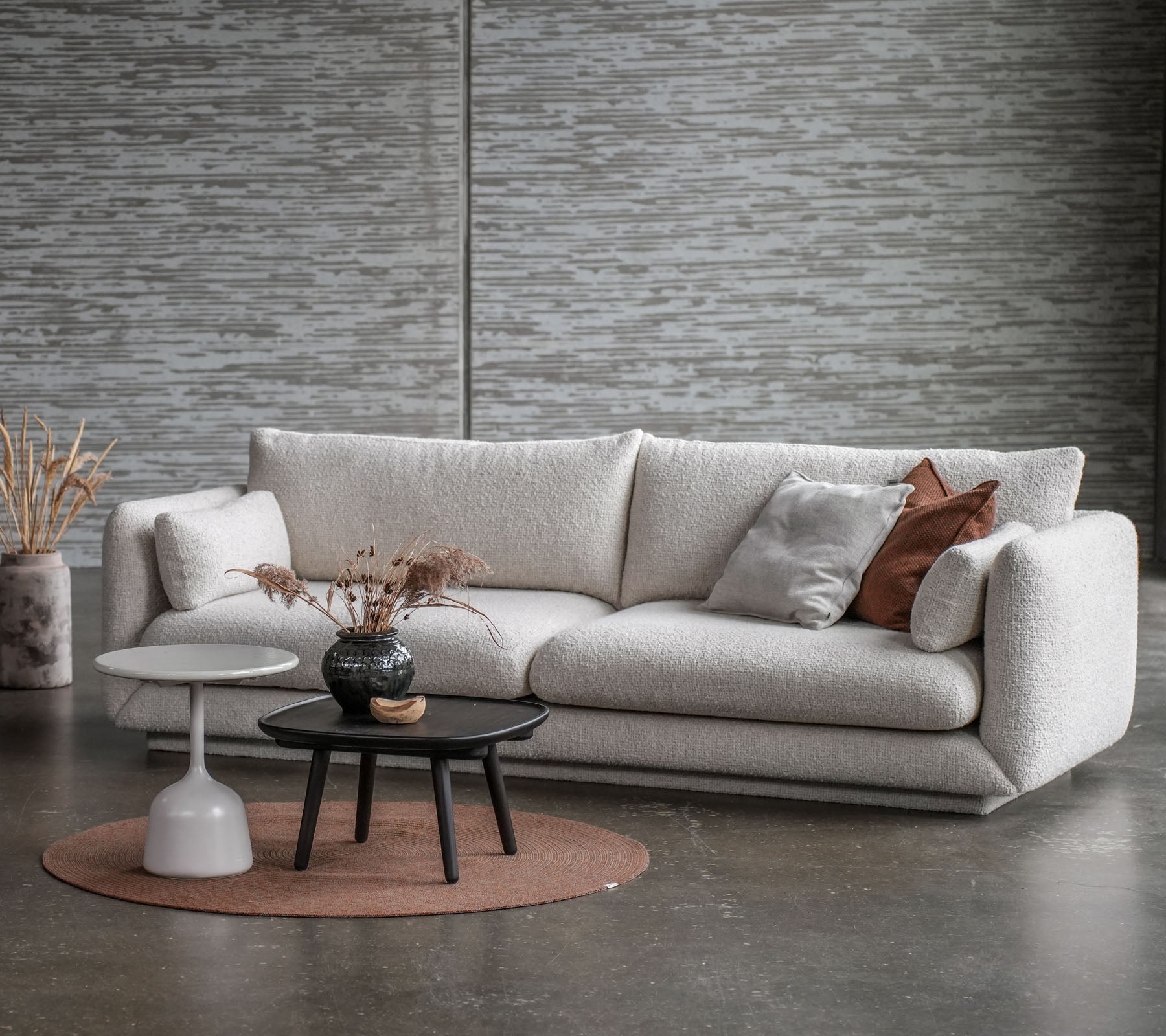 Un espace salon élégant avec un canapé clair, une table basse ronde et des éléments décoratifs dans des couleurs douces.