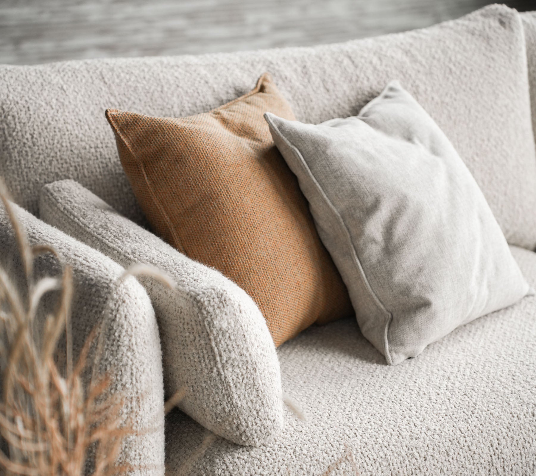 Canapé confortable avec Bloom dans une couleur sable et deux coussins, l'un beige et l'autre brun chaud, ajoutant une touche élégante.