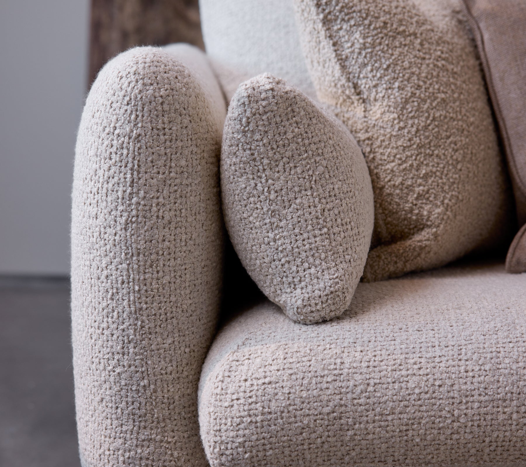 Gros plan du bras du canapé Bloom dans une texture sable flair, mettant en valeur un design arrondi et un tissu doux et confortable.