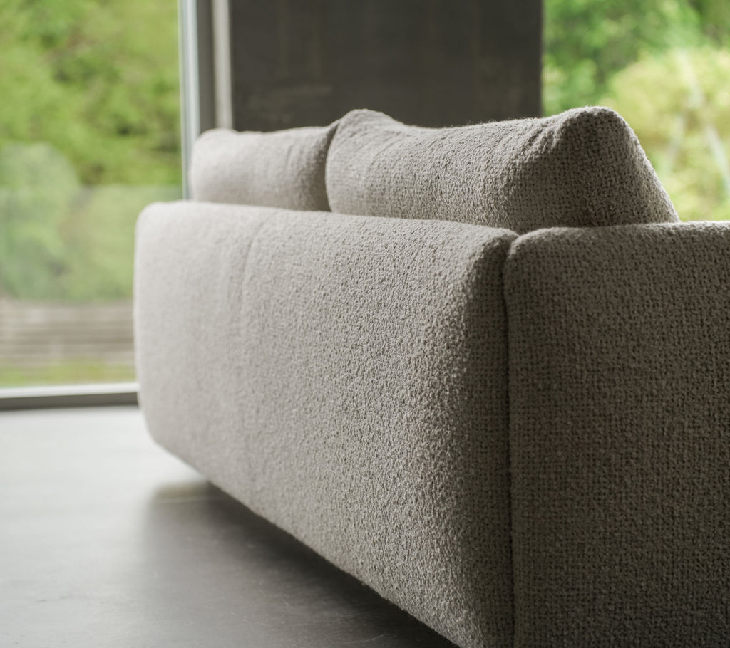 Canapé contemporain en tissu texturé couleur sable, accentué par des pieds en teck élégants, mettant en avant le style Cane-line et des coussins moelleux.