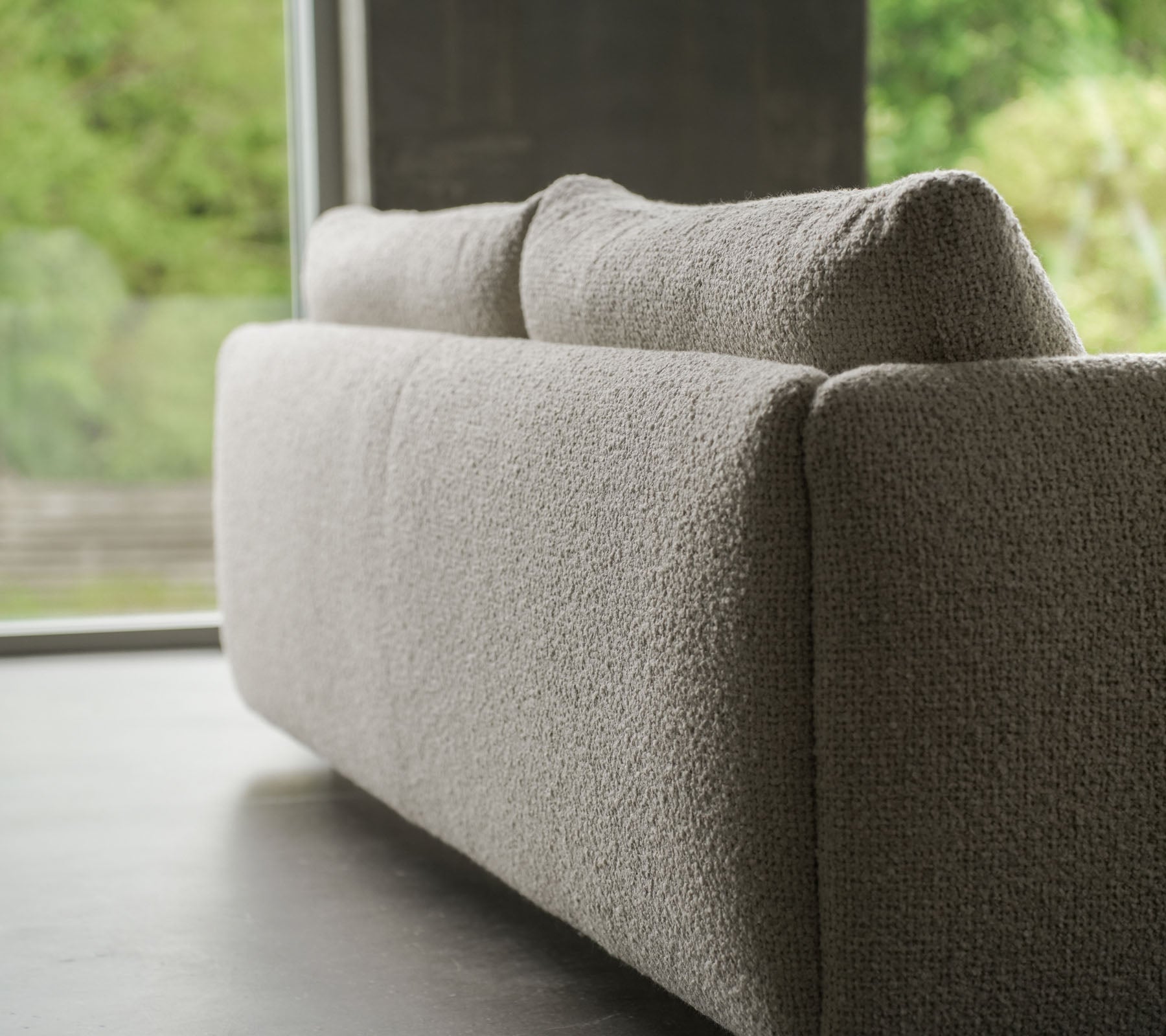 Canapé contemporain en tissu texturé couleur sable, accentué par des pieds en teck élégants, mettant en avant le style Cane-line et des coussins moelleux.