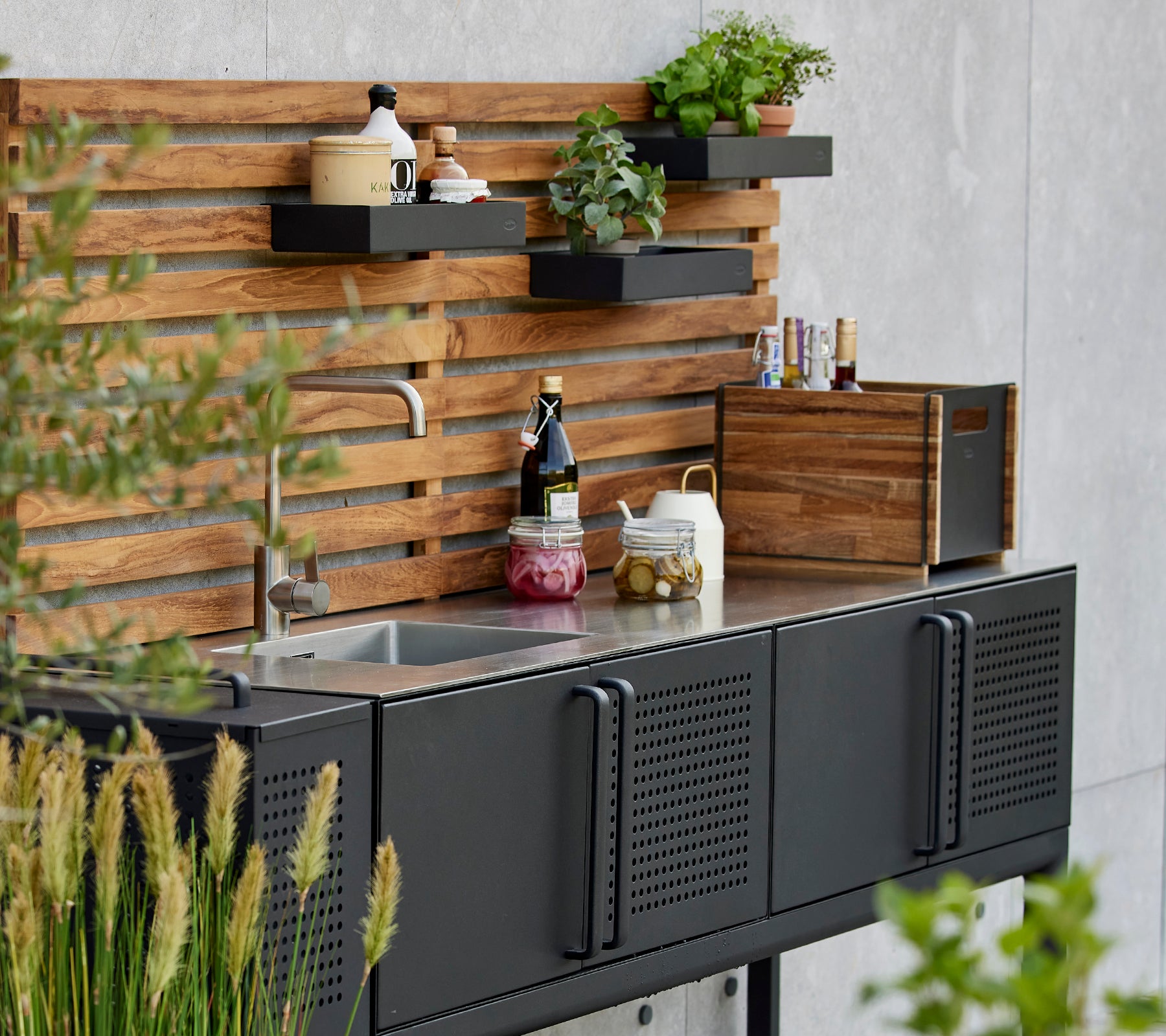 Boîte de rangement élégante sur un plan de travail de cuisine fonctionnel, avec des plantes et des condiments présentés sur un élégant fond en bois.