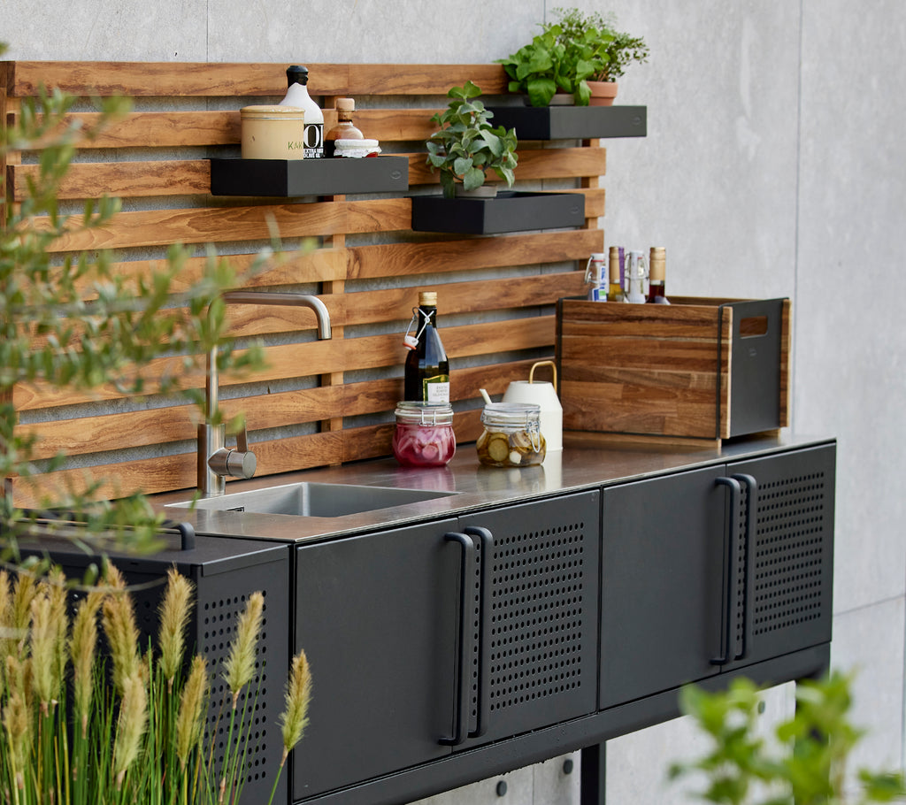 Boîte de rangement élégante sur un plan de travail de cuisine fonctionnel, avec des plantes et des condiments présentés sur un élégant fond en bois.