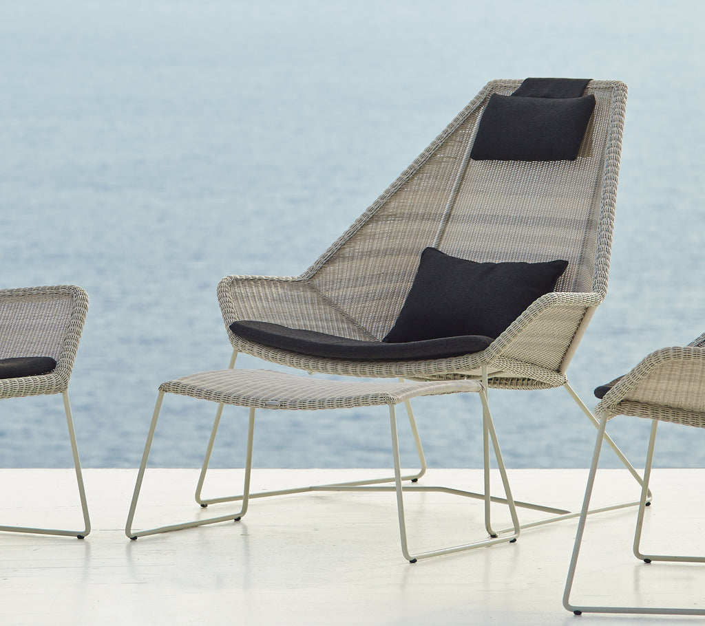 Chaise tissée moderne avec un coussin noir au bord de l'eau.