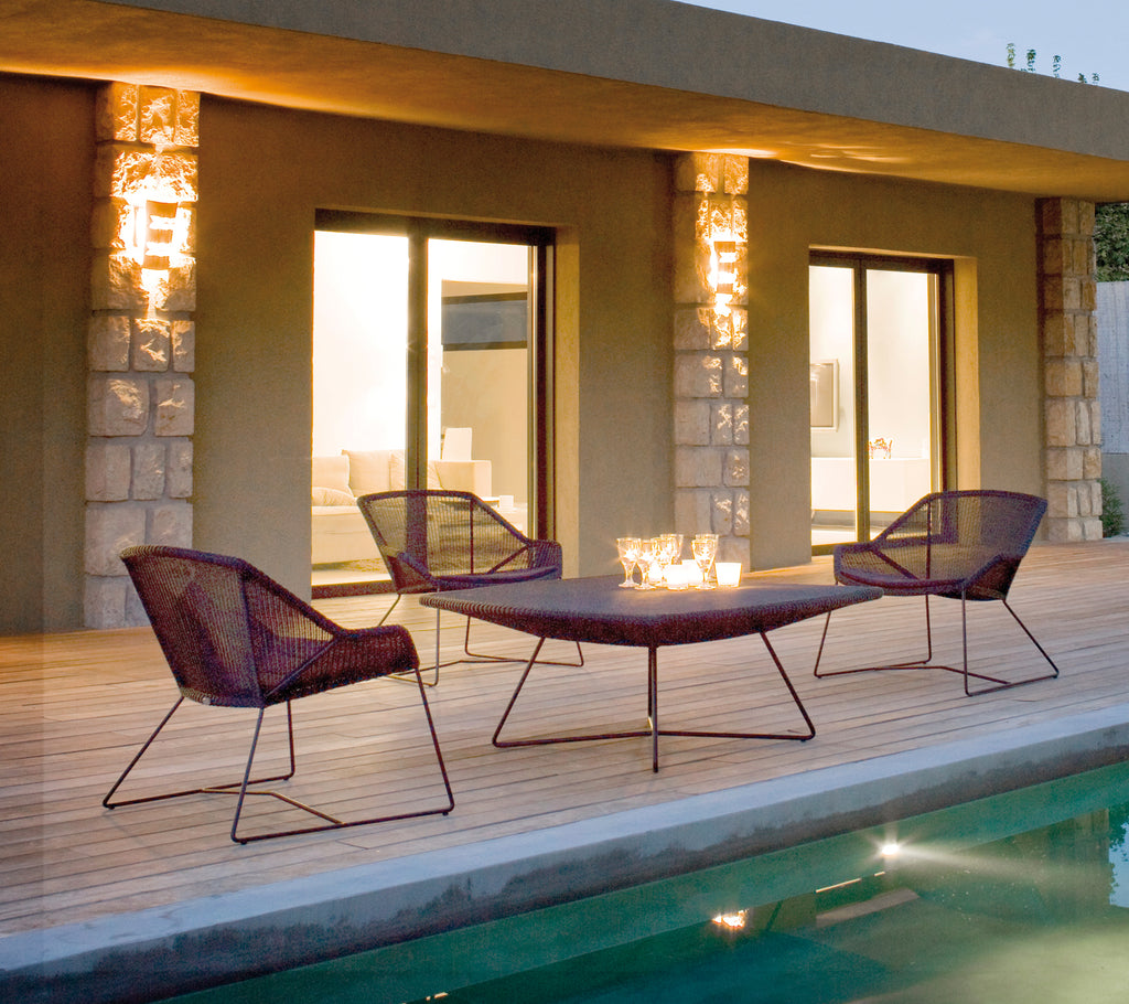 Environnement moderne en plein air avec des chaises longues violettes et une table assortie près d’une piscine.