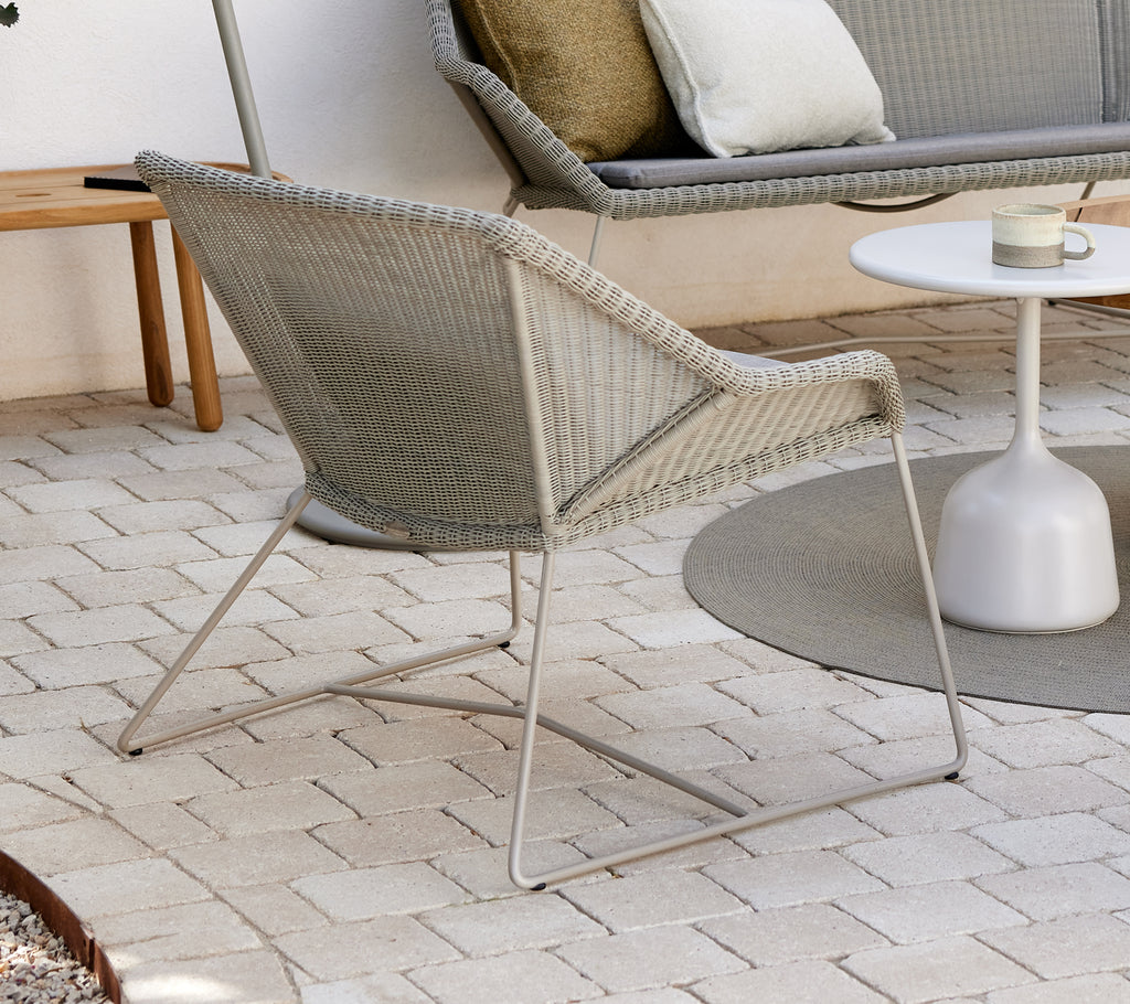 Fauteuil gris avec table d'appoint blanche dans un cadre extérieur moderne.