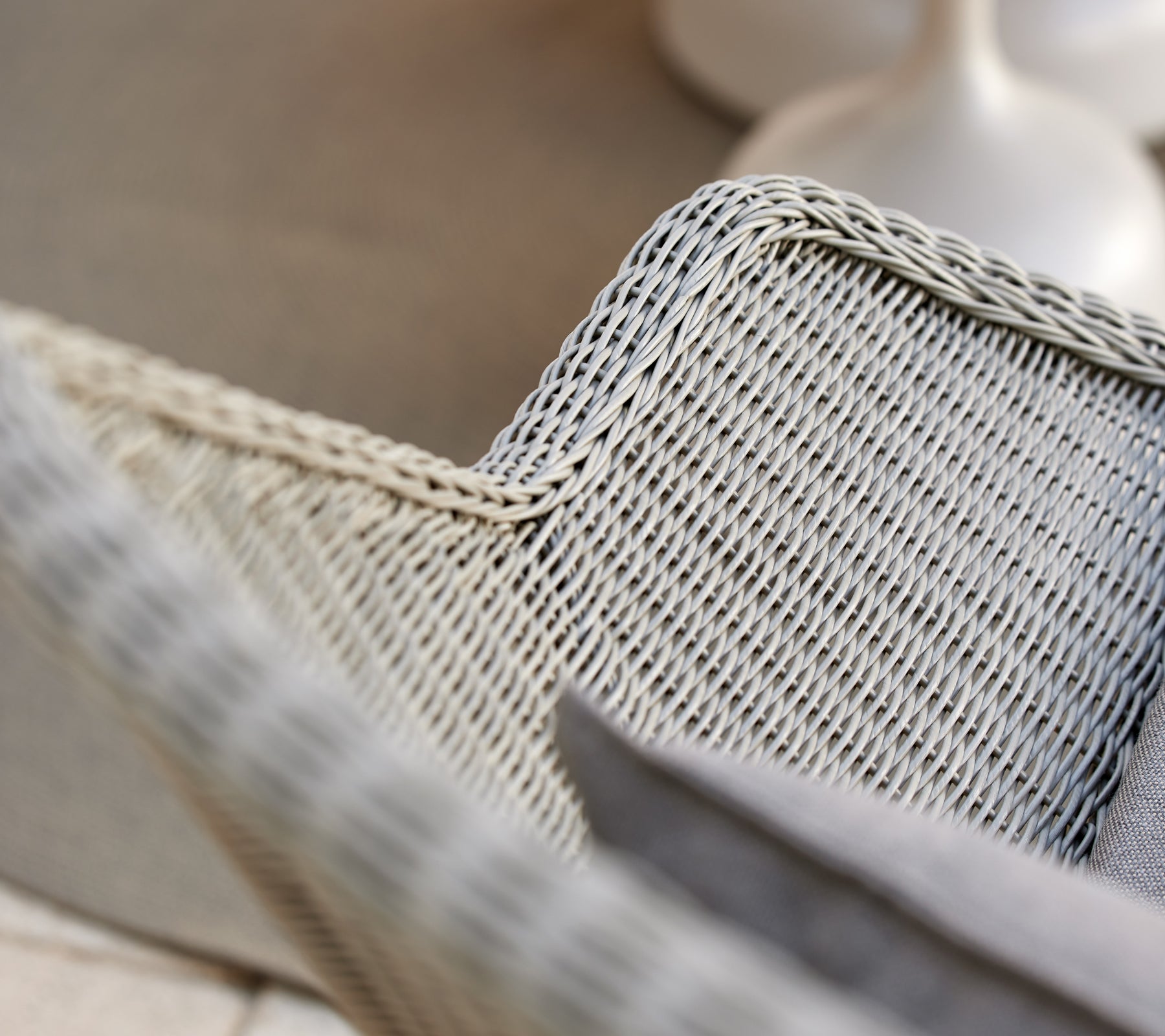 Fauteuil tissé gris avec un coussin gris.