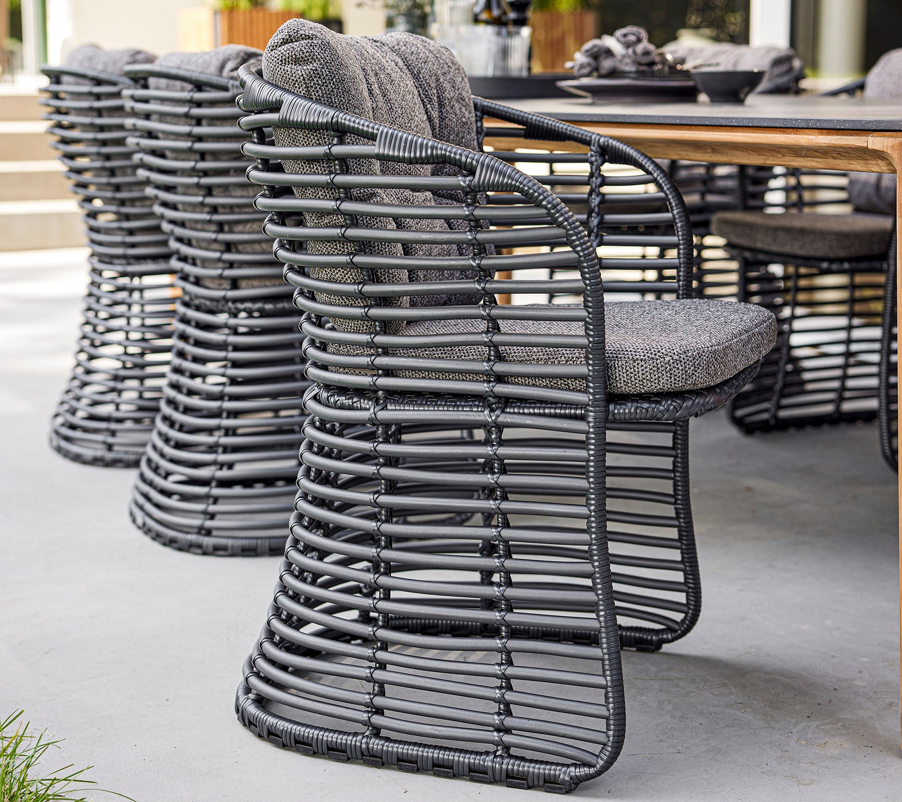 Chaises tissées élégantes avec un design moderne et des sièges rembourrés, disposées à côté d'une table en bois.