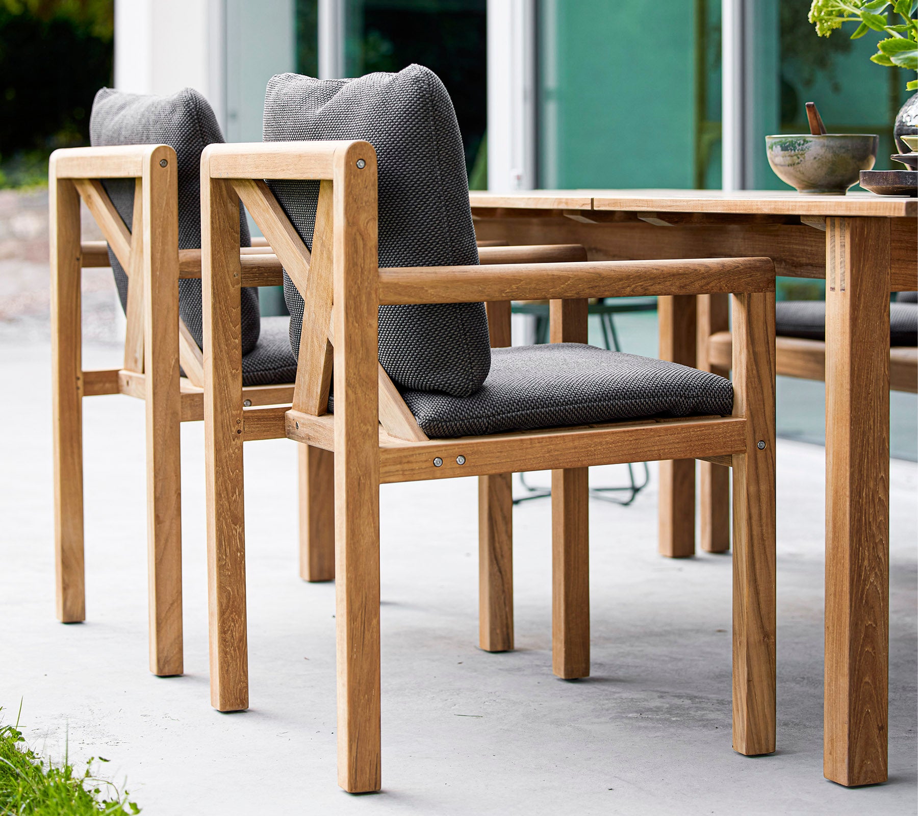Chaises en bois avec des sièges en tissu gris, conçues pour le confort, complétant une table en bois dans un cadre élégant.