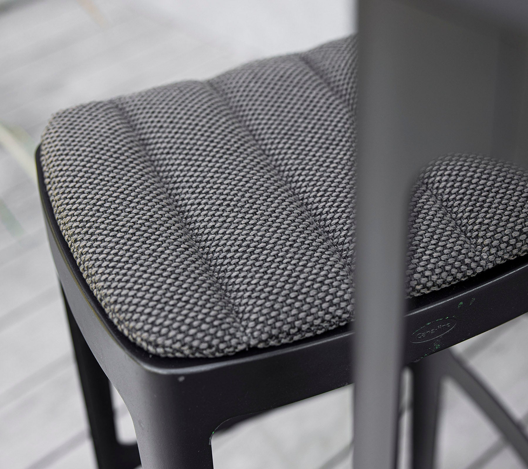 Gros plan d'un siège de chaise noir texturé avec un design matelassé, mettant en valeur le savoir-faire moderne et l'attention portée aux détails.