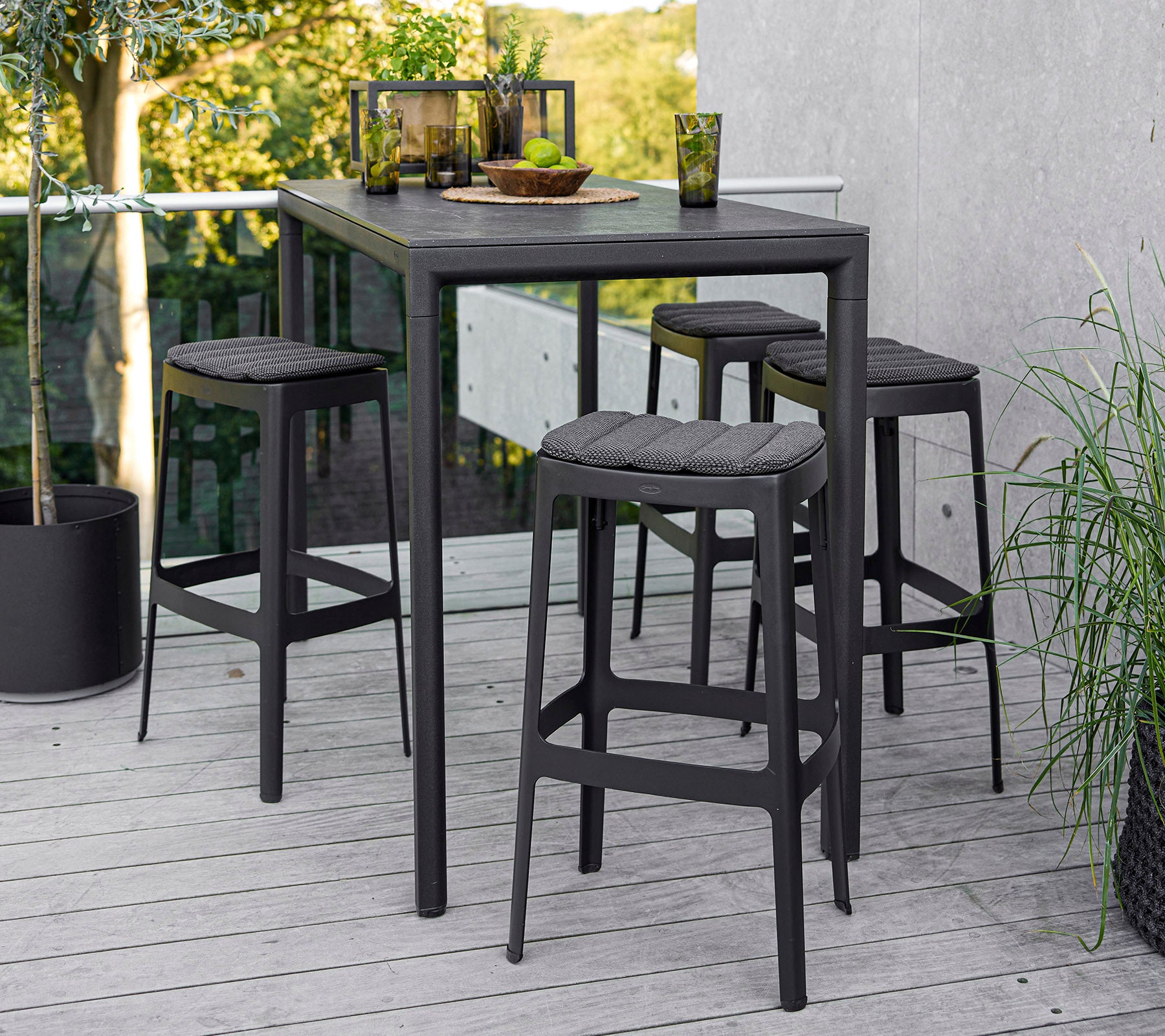 Une table moderne avec quatre tabourets assortis, présentant un design épuré et une esthétique minimaliste, sur fond naturel.