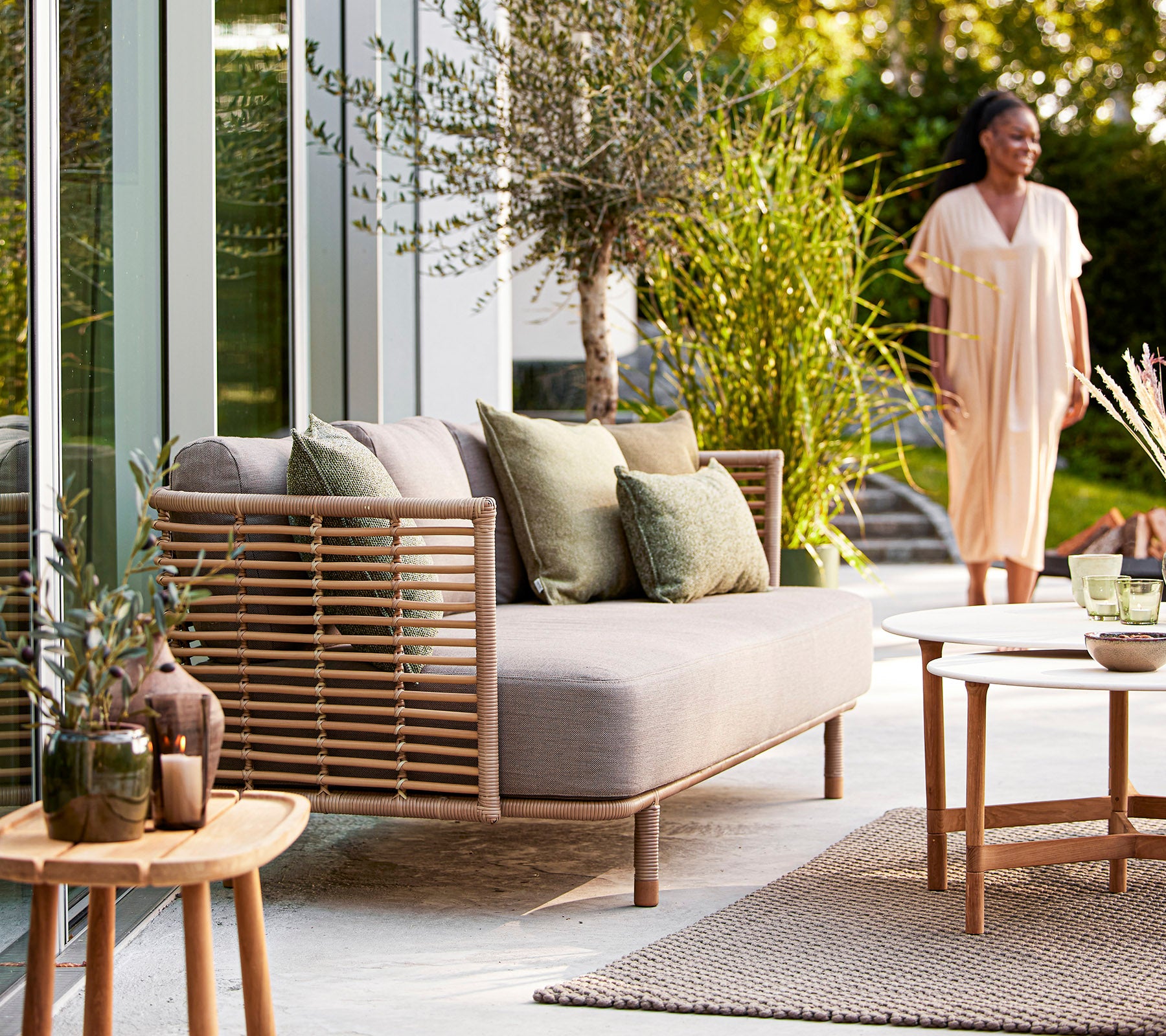 Un coin salon confortable avec un canapé clair, des coussins verts, des plantes décoratives et une table en bois, créant une atmosphère accueillante.