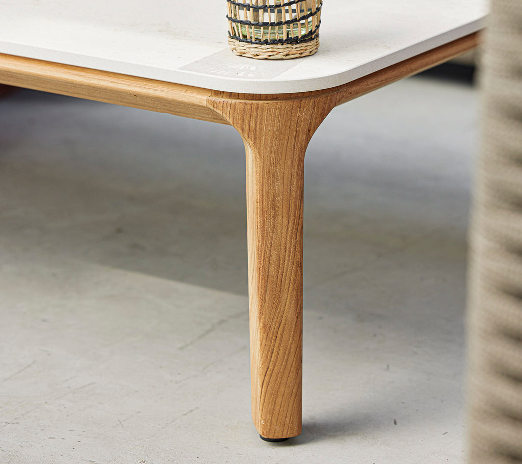 Une table élégante avec une surface lisse et une jambe en bois naturel, surmontée d'un panier tressé décoratif.
