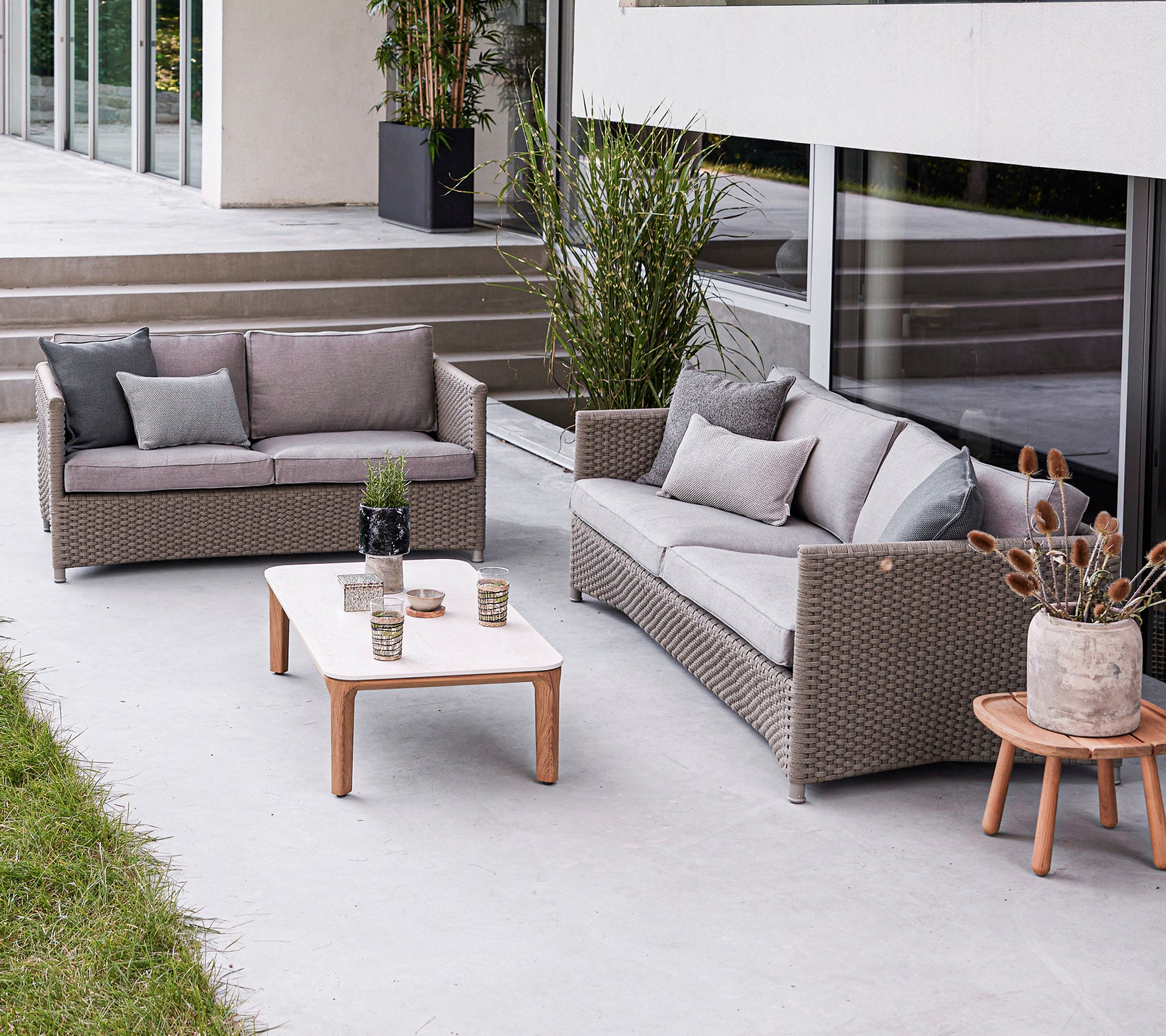 Aménagement moderne de sièges extérieurs avec un canapé, un loveseat et une table basse avec des éléments décoratifs. Atmosphère élégante et accueillante.