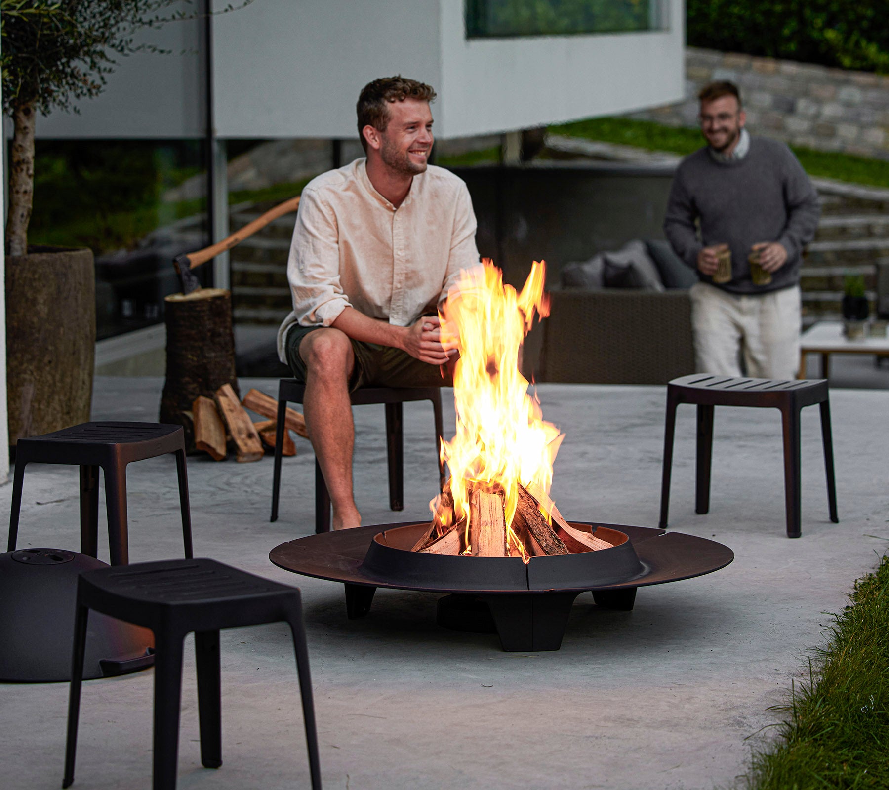 Deux hommes profitent d'un foyer entouré de sièges modernes, créant une atmosphère cozy pour la détente et la conversation.